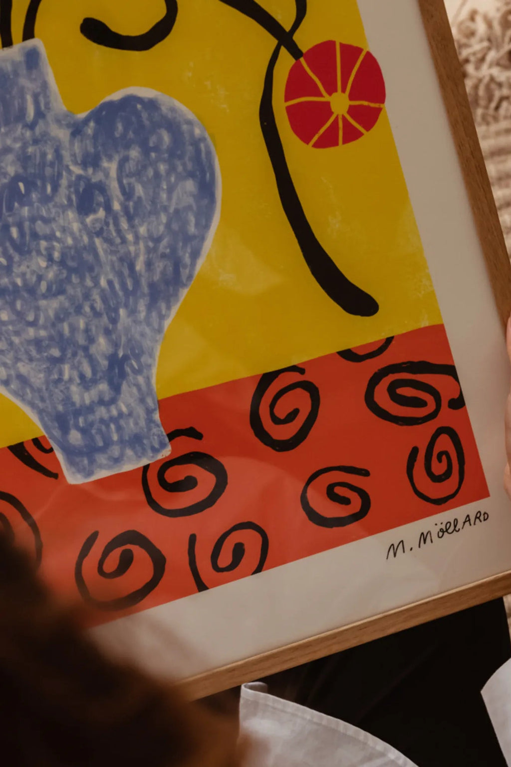 The Poster Club Flowers in Blue Vase, a vibrant abstract art print featuring a textured dark blue vase set against a bold yellow background, with a red flower or fruit on a black stem, and a lower section in coral red with black swirling patterns. This colorful contemporary poster, framed in a light natural oak frame with a white mat, captures a playful, Matisse-inspired aesthetic, perfect for modern living rooms, bedrooms, or gallery walls.
