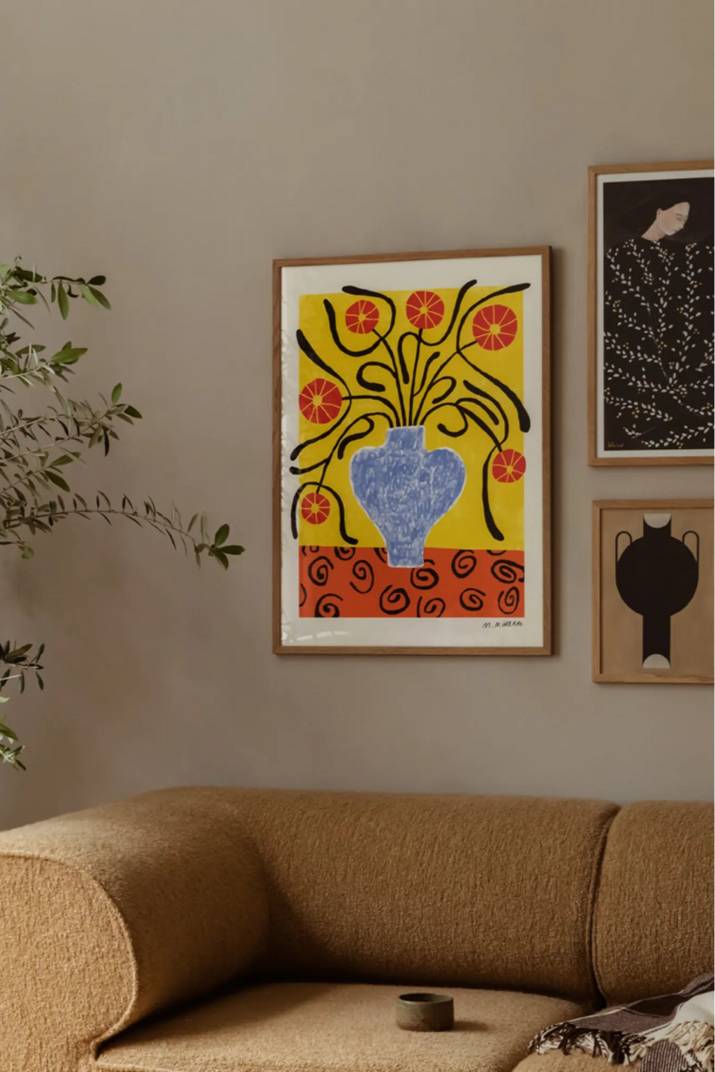 The Poster Club Flowers in Blue Vase, a vibrant modern abstract art print featuring a textured royal blue vase filled with graphic black stems and red flowers against a bright yellow background, with an orange patterned base. This bold, graphic illustration is framed in natural oak with a white mat, making it perfect for contemporary gallery walls or adding a pop of color to modern living rooms.