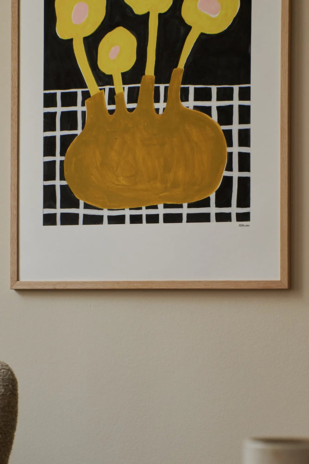 The Poster Club Flowers In Brown Vase, a modern abstract art print featuring bold mustard yellow organic shapes resembling flowers in an abstract vase, accented with subtle pale pink details. This graphic contemporary wall art is set against a striking black and white grid background, framed in a light natural oak frame with a crisp white mat. Ideal for minimalist living rooms, Scandinavian bedrooms, or adding a pop of color to a gallery wall.