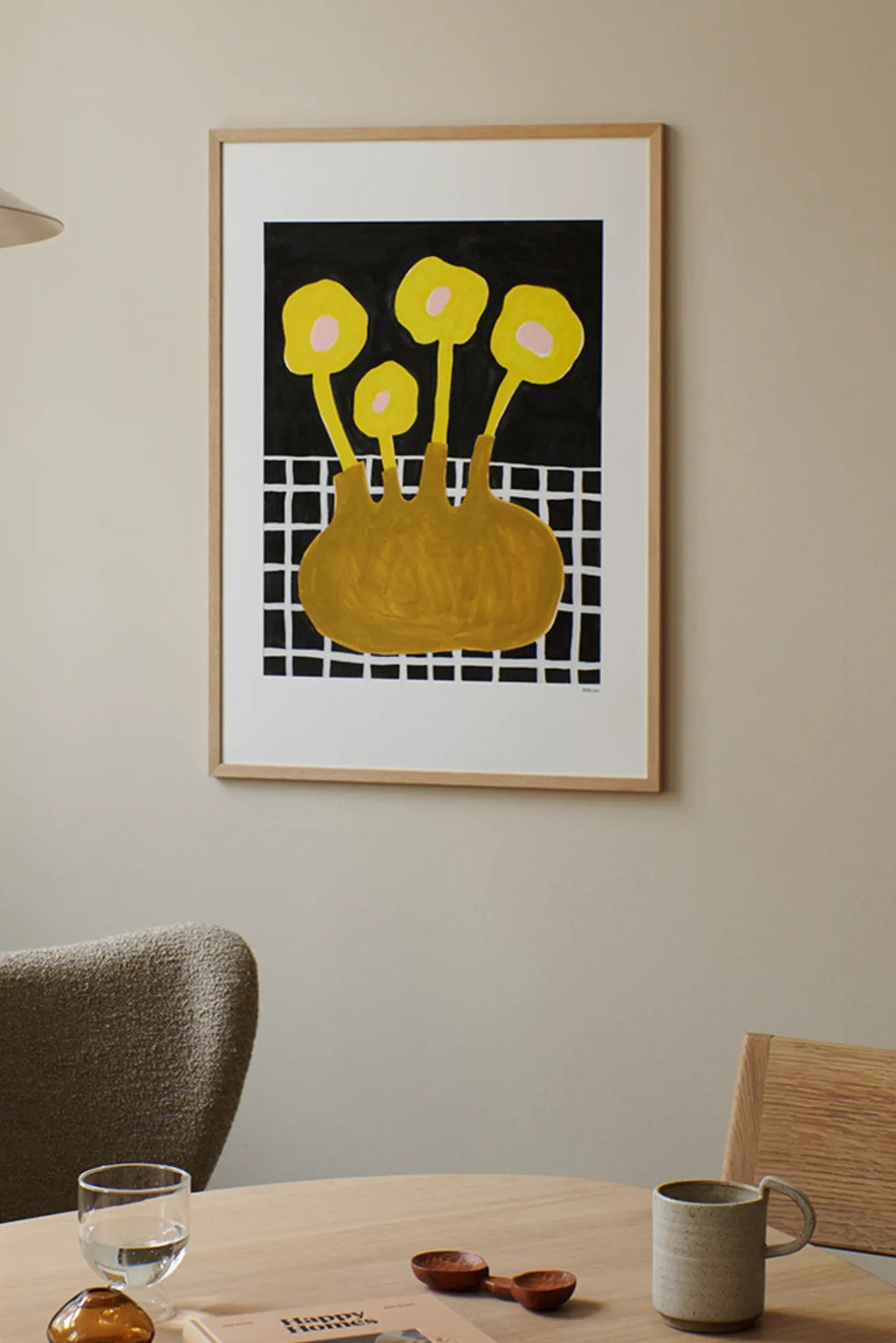 The Poster Club Flowers In Brown Vase, an abstract art print featuring graphic mustard yellow flowers with light pink centers emerging from rounded vase shapes, set against a dark black background with a white grid pattern, framed in a light natural oak frame. Perfect as modern wall art for contemporary living rooms, dining spaces, or gallery walls.