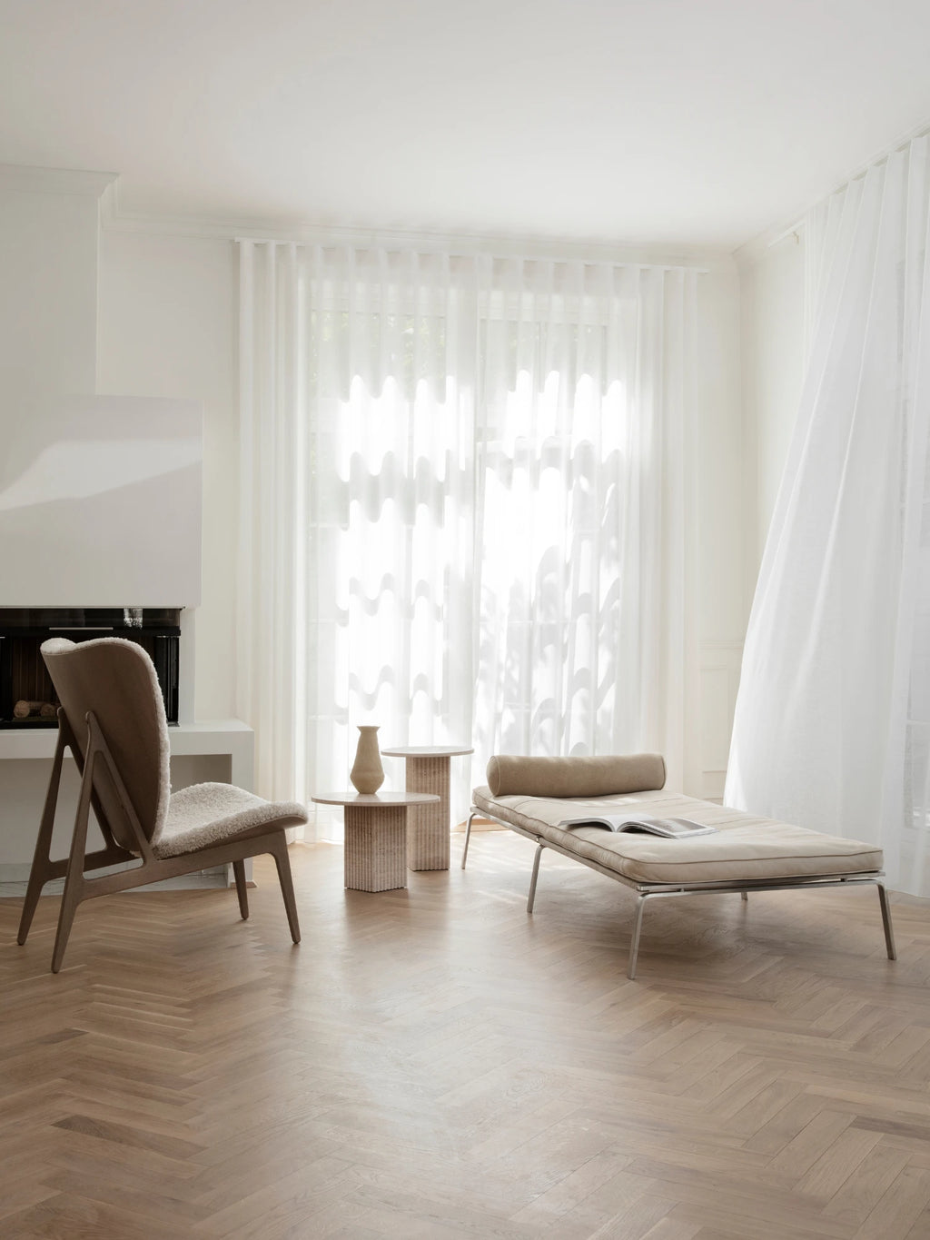 NORR11 Man Daybed, a modern minimalist daybed featuring light beige fabric upholstery with a sleek stainless steel frame and a matching cylindrical bolster cushion. Its clean lines and low-profile design make it perfect as a contemporary chaise lounge for Scandinavian living rooms or stylish home offices.