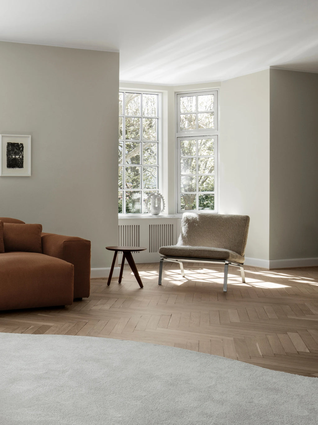 NORR11 Man Lounge Chair, a modern minimalist lounge chair featuring a low-slung profile with a plush, long-pile sheepskin-style upholstery in a natural taupe tone, supported by a sleek brushed chrome metal frame. This contemporary accent chair is ideal for Scandinavian living rooms, cozy reading nooks, or sophisticated bedroom corners.