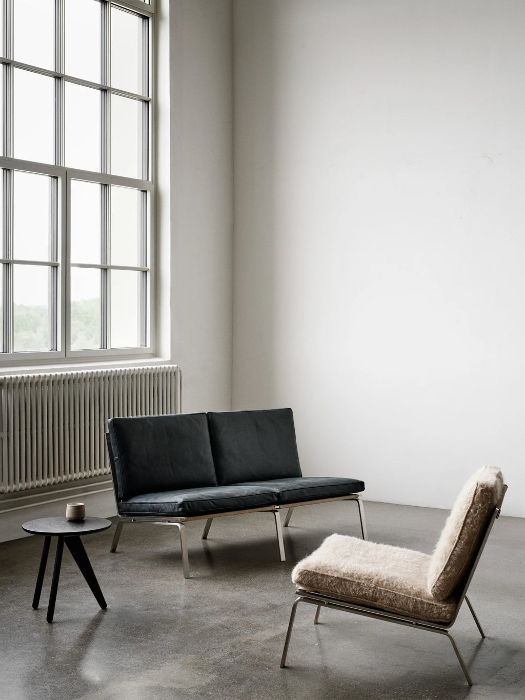 NORR11 Man Lounge Chair, a mid-century modern accent chair featuring plush cream fuzzy upholstery with a shaggy texture, set on a sleek brushed steel frame with angled legs. This minimalist lounge chair offers a low-slung profile and clean Scandinavian design. Perfect as a cozy living room lounge chair or contemporary bedroom accent piece.