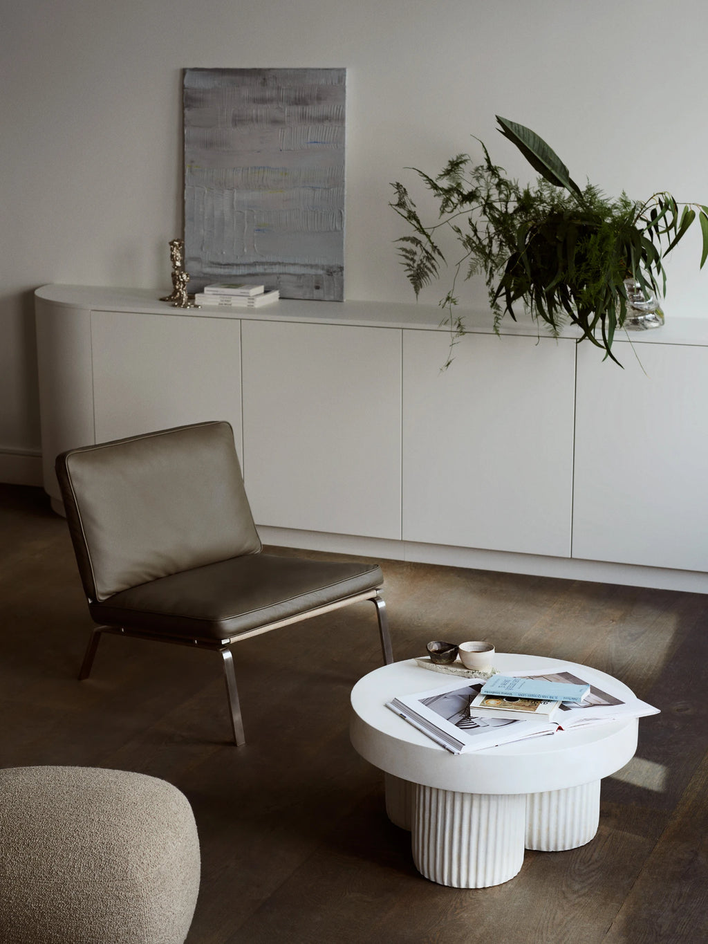 NORR11 Man Lounge Chair, a sleek modern minimalist lounge chair featuring a low-slung profile and contemporary design. It has khaki green leather upholstery with refined piping details, supported by a polished silver metal frame with slender angled legs. Ideal as a stylish accent chair for modern living rooms or a sophisticated reading nook.