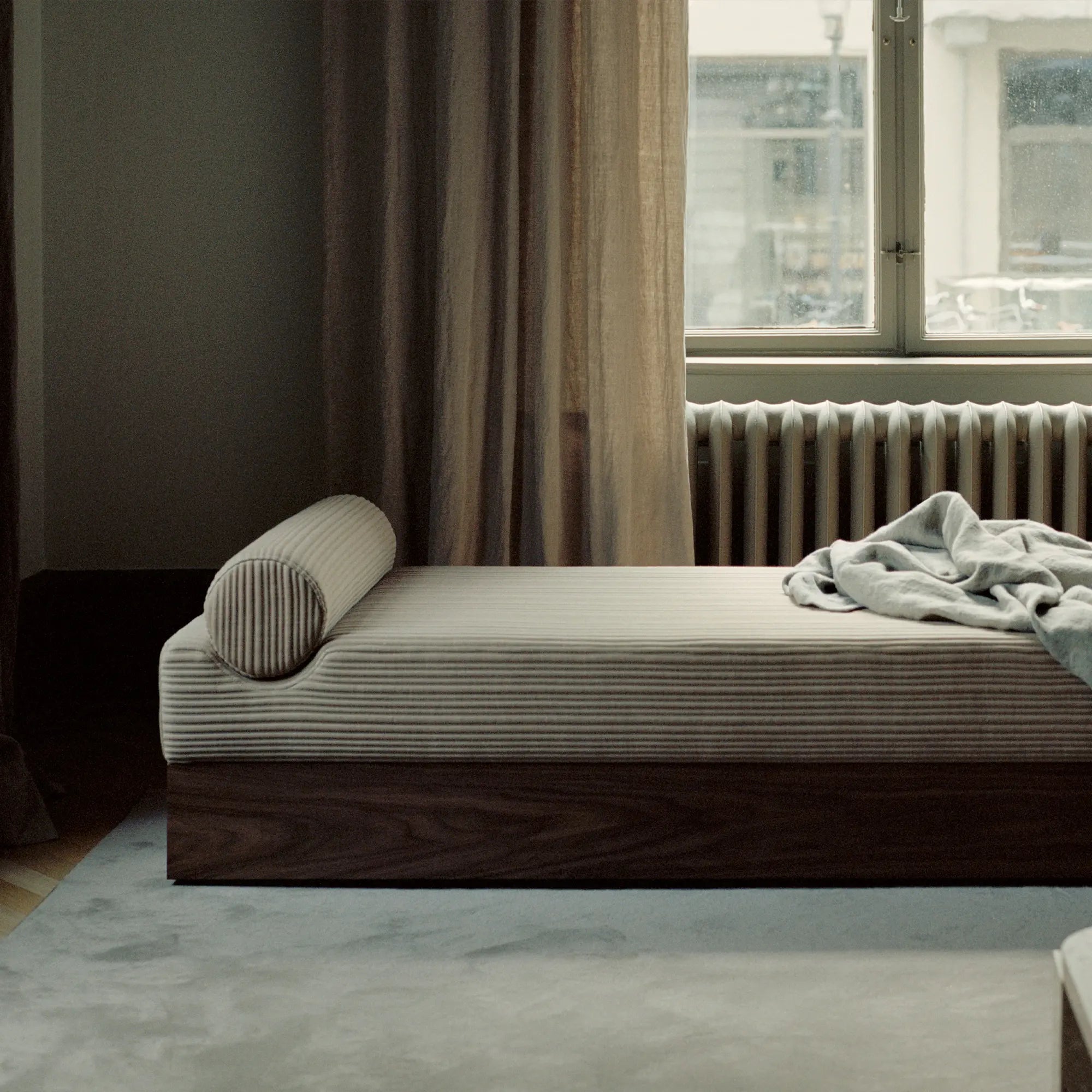  Sleek and versatile mass daybed in beige fabric with wooden frame and bolster cushions for relaxation 