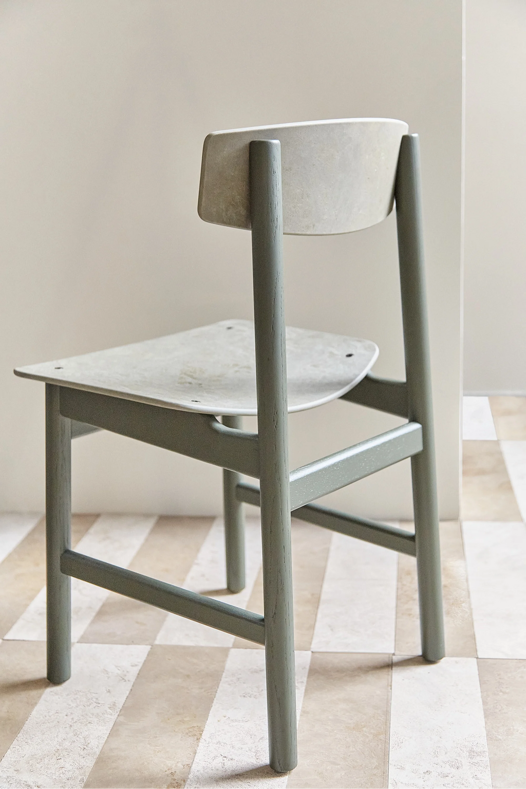 Mater Conscious Chair in green stained oak, Coffee Green finish. Close-up back view showcasing the smooth, durable recycled plastic seat and backrest, paired with a solid oak frame, displayed on a checkered floor.
