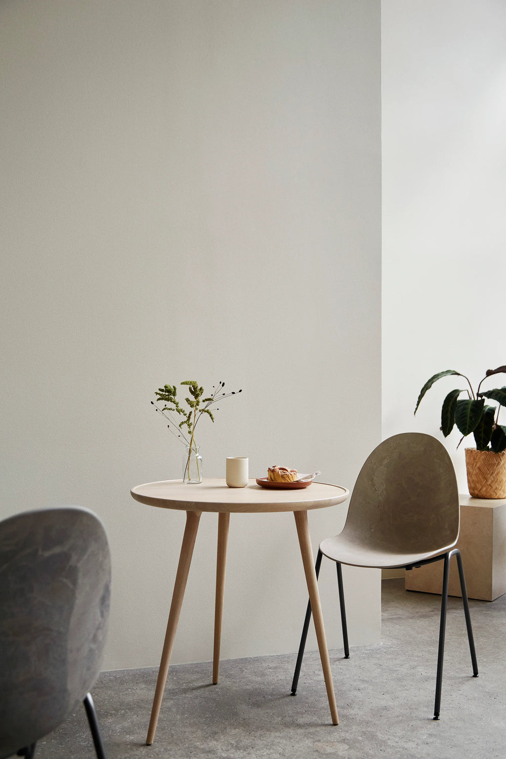 Mater Eternity Sidechair in a modern cafe setting, featuring a dark gray textured seat and sleek black metal legs, paired with a light wood accent table. The chair's ergonomic design and durable materials are highlighted, creating a stylish and comfortable dining experience.