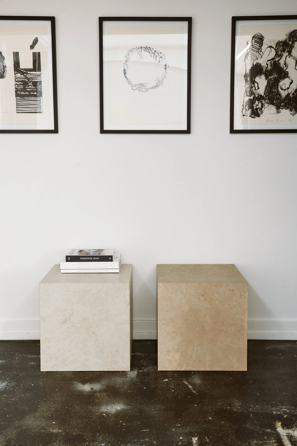 Mater Cube, two elegant cube-shaped side tables in light beige and cream tones, featuring a subtle marbled texture, positioned in a bright, modern room with framed art.