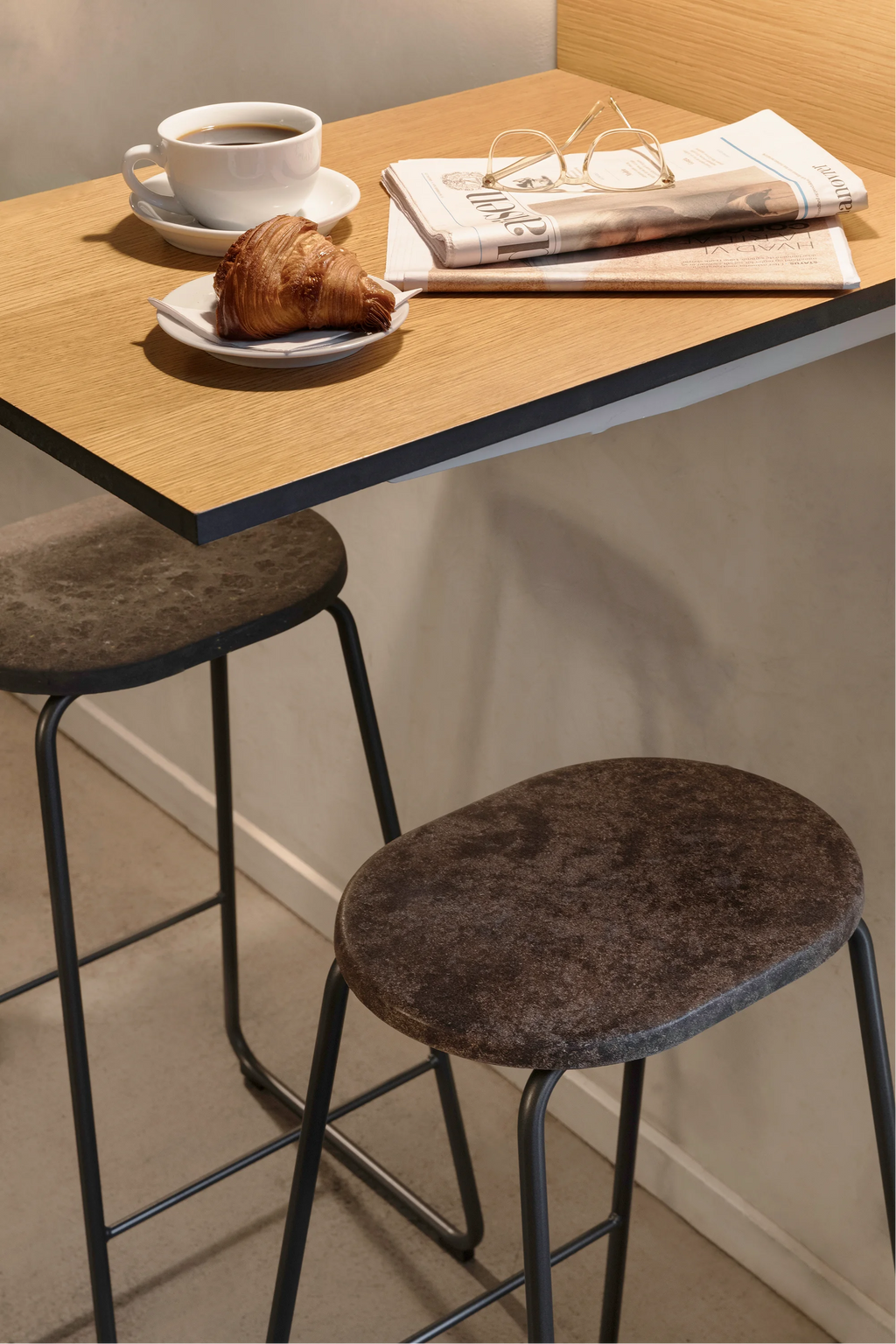 Mater Earth Counter Stool, a close-up view revealing the unique dark grey, mottled seat texture made from recycled materials, paired with sleek black metal legs, offering a modern, sustainable design.