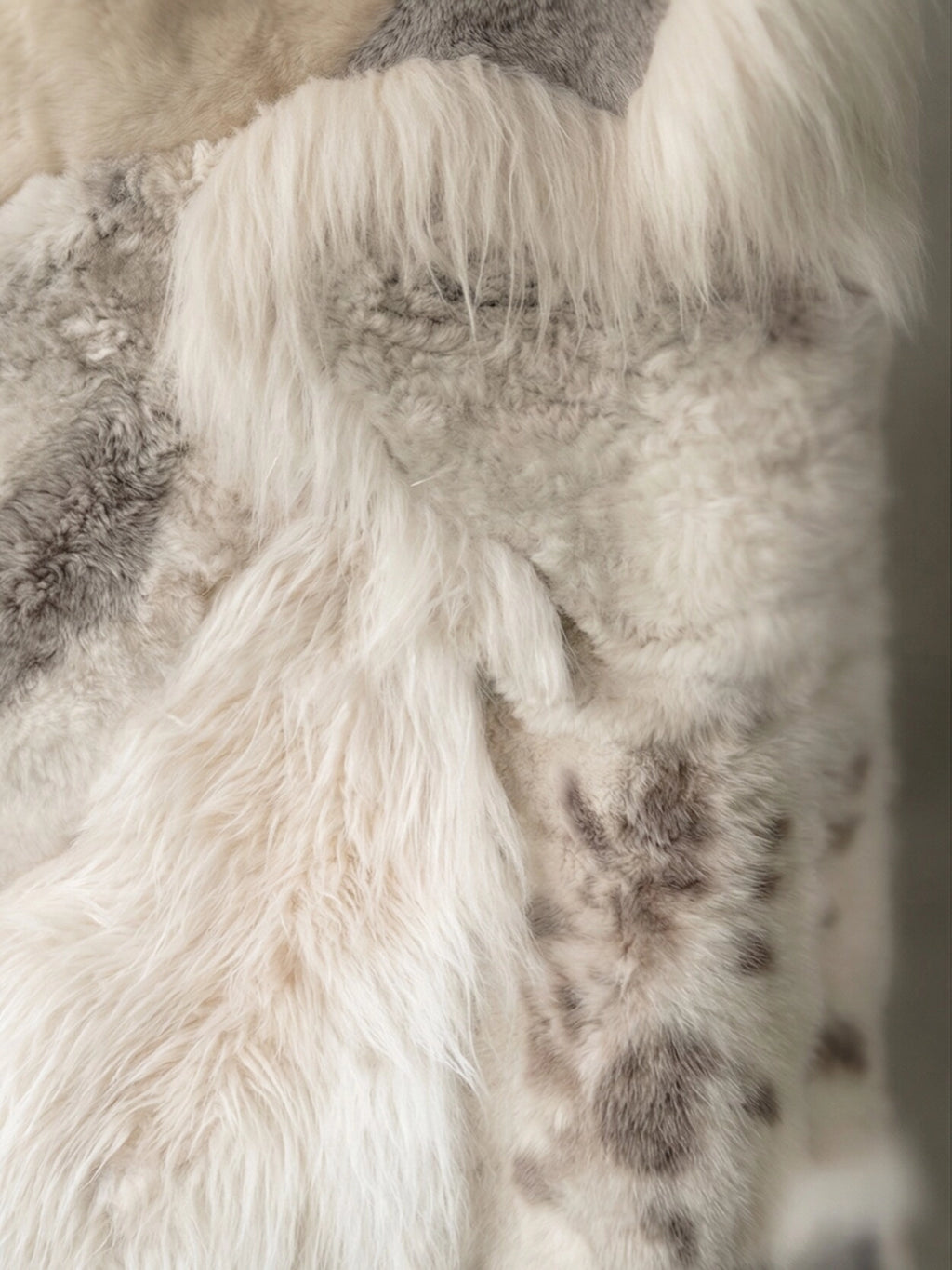 TCL Studios Melange Sheepskin Patchwork Rug, a luxurious natural sheepskin rug featuring a soft, shaggy texture with varied pile lengths and a beautiful melange of cream, off-white, and mottled grey-brown tones in a unique patchwork design. This cozy sheepskin rug is ideal for adding warmth and organic modern style to Scandinavian bedrooms, rustic living rooms, or hygge-inspired spaces.