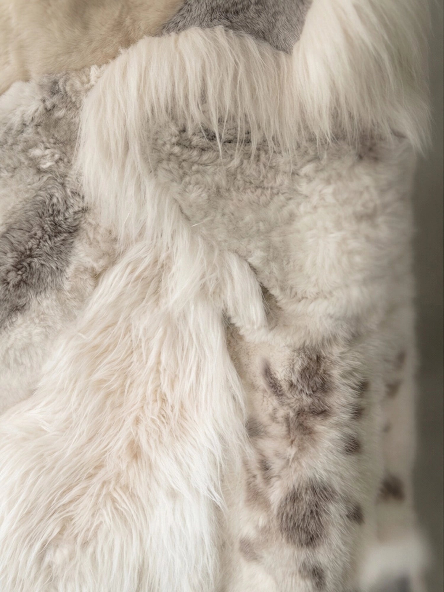 TCL Studios Melange Sheepskin Patchwork Rug, a luxurious natural sheepskin rug featuring a soft, shaggy texture with varied pile lengths and a beautiful melange of cream, off-white, and mottled grey-brown tones in a unique patchwork design. This cozy sheepskin rug is ideal for adding warmth and organic modern style to Scandinavian bedrooms, rustic living rooms, or hygge-inspired spaces.