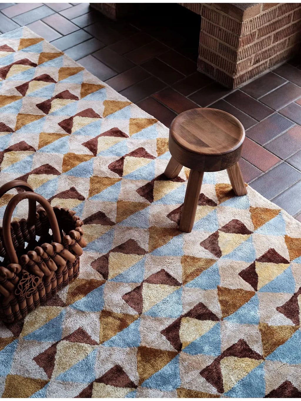 Tinted Objects Mellin Viscose Rug, a plush, textured area rug featuring a modern geometric triangle pattern in shades of light blue, golden yellow, chocolate brown, and cream. This stylish rug is perfect for adding warmth and contemporary design to living rooms or bedrooms for design-conscious homeowners.