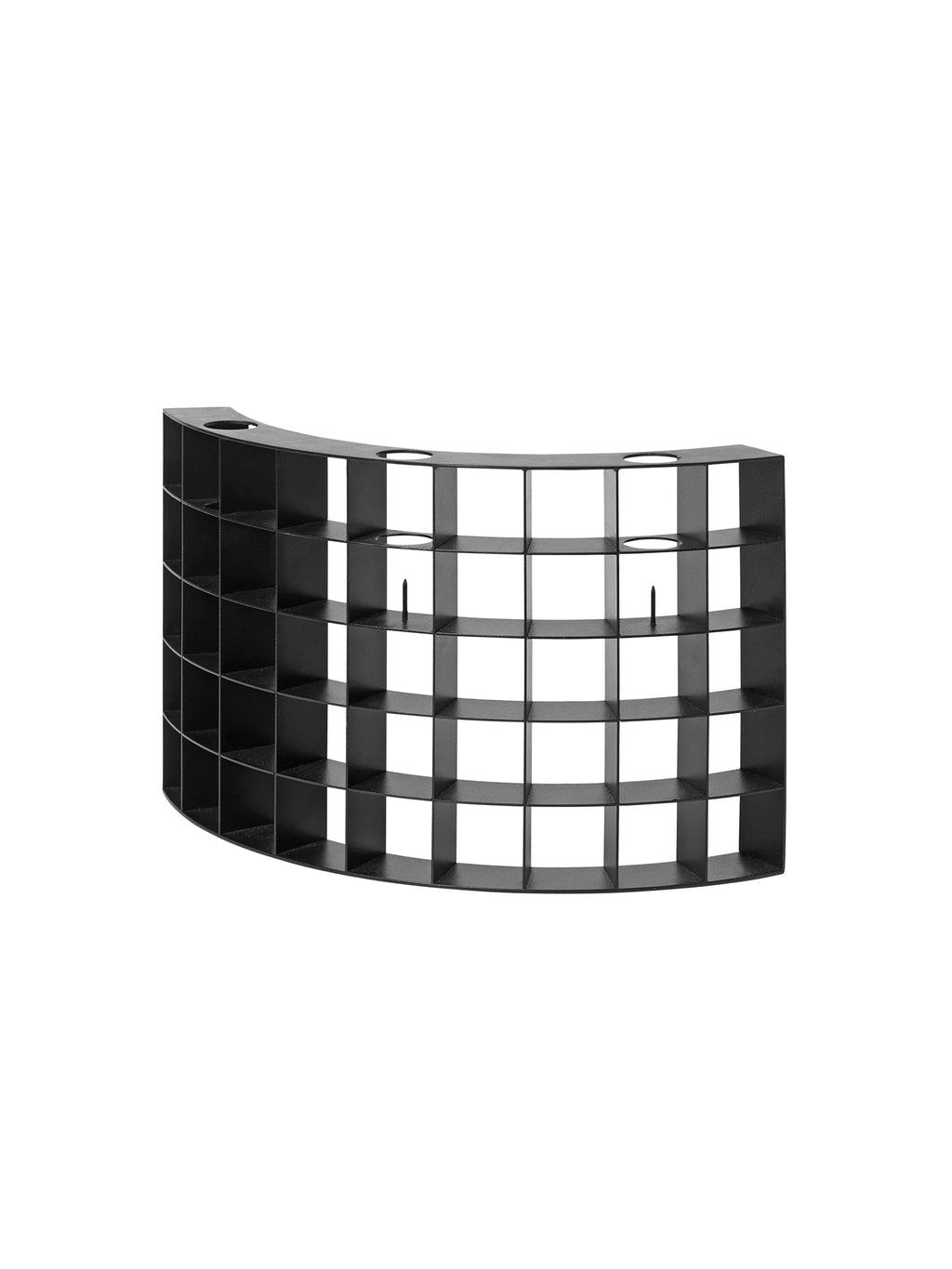 Kristina Dam Mesh Candle Holder, a bold matte black metal candle holder crafted from powder-coated steel with a unique curved, semi-circular grid design. It features multiple square compartments and circular openings on the top surface, some with central spikes, designed to hold pillar candles. Perfect as a modern minimalist centerpiece, industrial chic shelf styling accent, or brutalist decorative object for contemporary interiors.