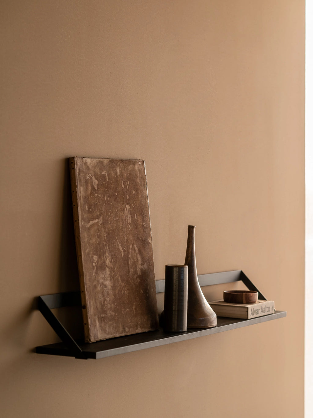 Ethnicraft Ribbon Shelf, a sleek modern minimalist wall shelf crafted from matte black metal with a distinctive integrated ribbon-like support design. This contemporary floating shelf offers a clean display solution for books and decor. Perfect for industrial chic living rooms, home office organization, or minimalist shelf styling.