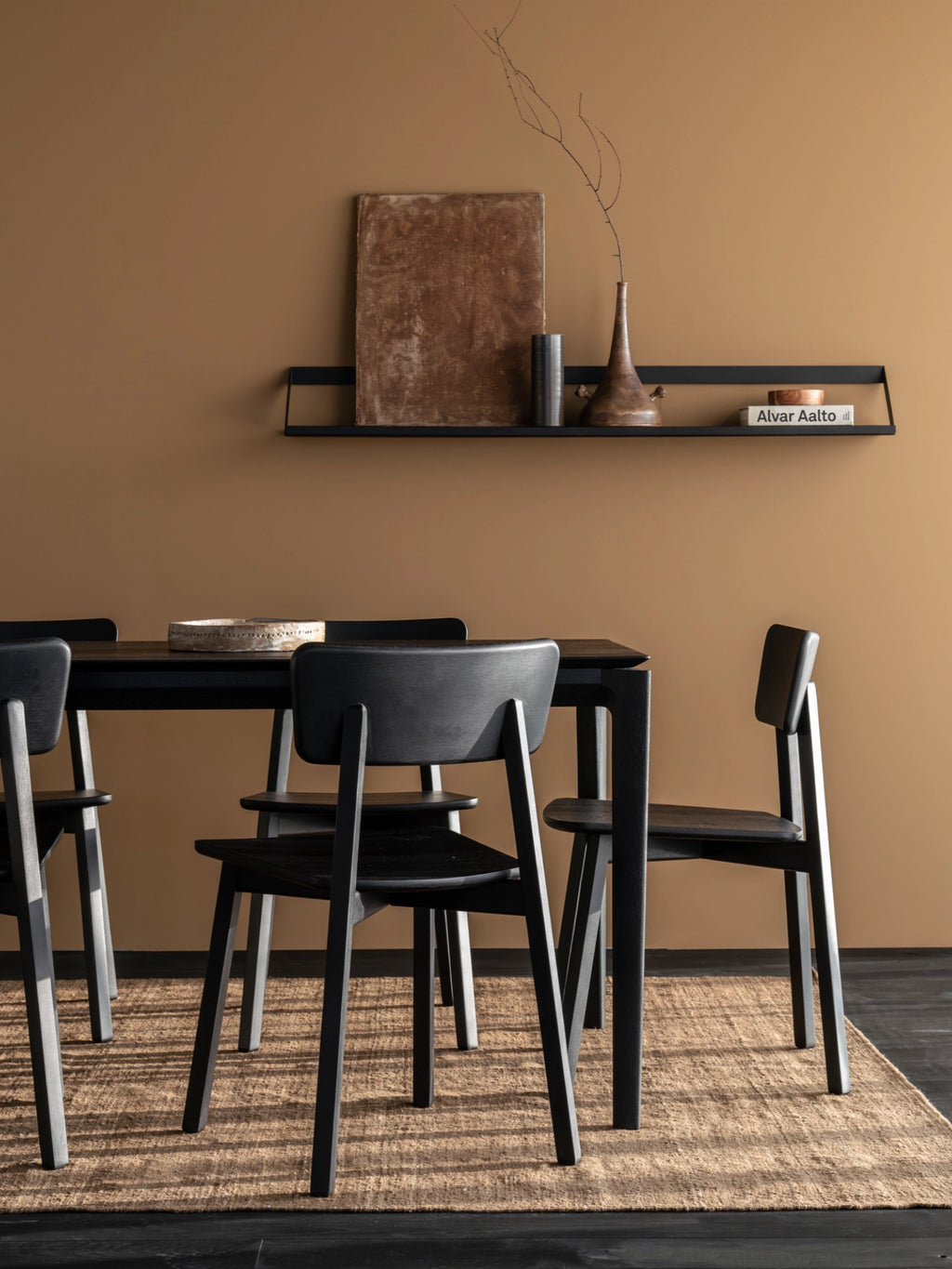 Ethnicraft Ribbon Shelf, a sleek matte black metal wall shelf featuring a minimalist linear design with a subtle upward-curved front lip, creating an elegant "ribbon" effect. This contemporary floating shelf provides stylish display storage for modern living rooms, Scandinavian dining areas, or minimalist home office spaces.