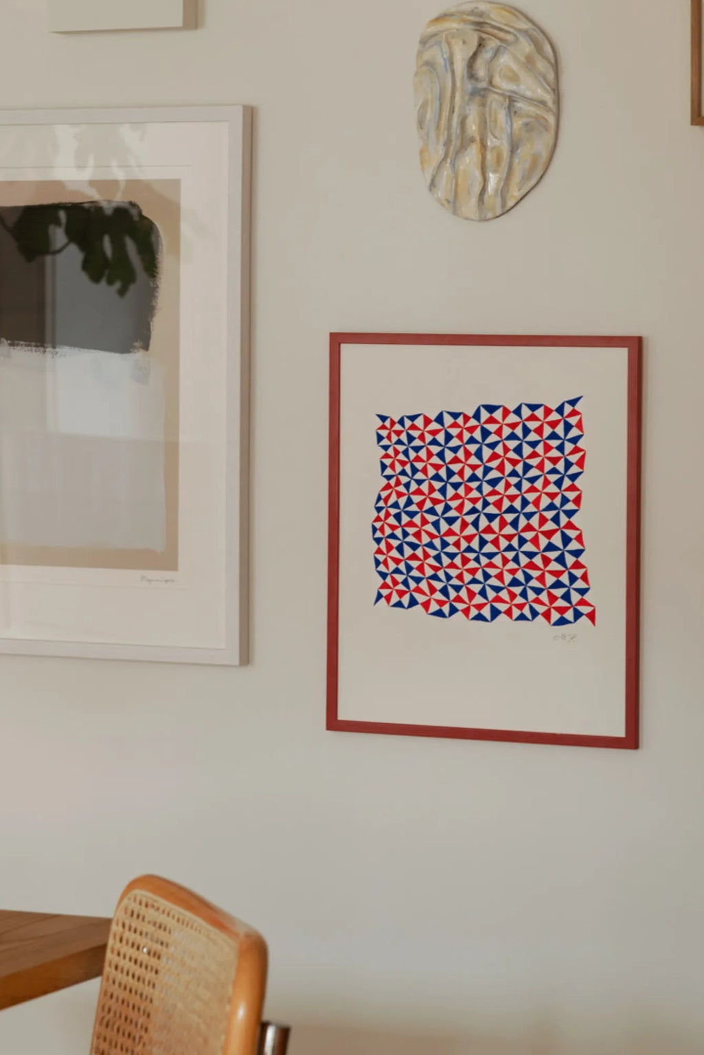 The Poster Club Tern No. 3, a vibrant abstract art print featuring a dynamic geometric pattern of alternating red and blue triangles arranged in a pinwheel design on a crisp white background, framed in a slim reddish-brown wood frame. This eye-catching contemporary wall art is ideal for adding a pop of color to modern living rooms, creative home offices, or eclectic gallery walls.