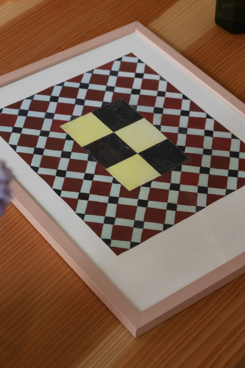 The Poster Club Tern No. 7, a vibrant geometric abstract art print featuring a bold central yellow and black checkerboard diamond layered over a background of smaller dark red, light blue, and black checkered squares. This modern graphic art print is presented with a crisp white mat and framed in a slim, light pink frame. Perfect as eye-catching wall art for contemporary gallery walls, living rooms, or creative home office spaces.