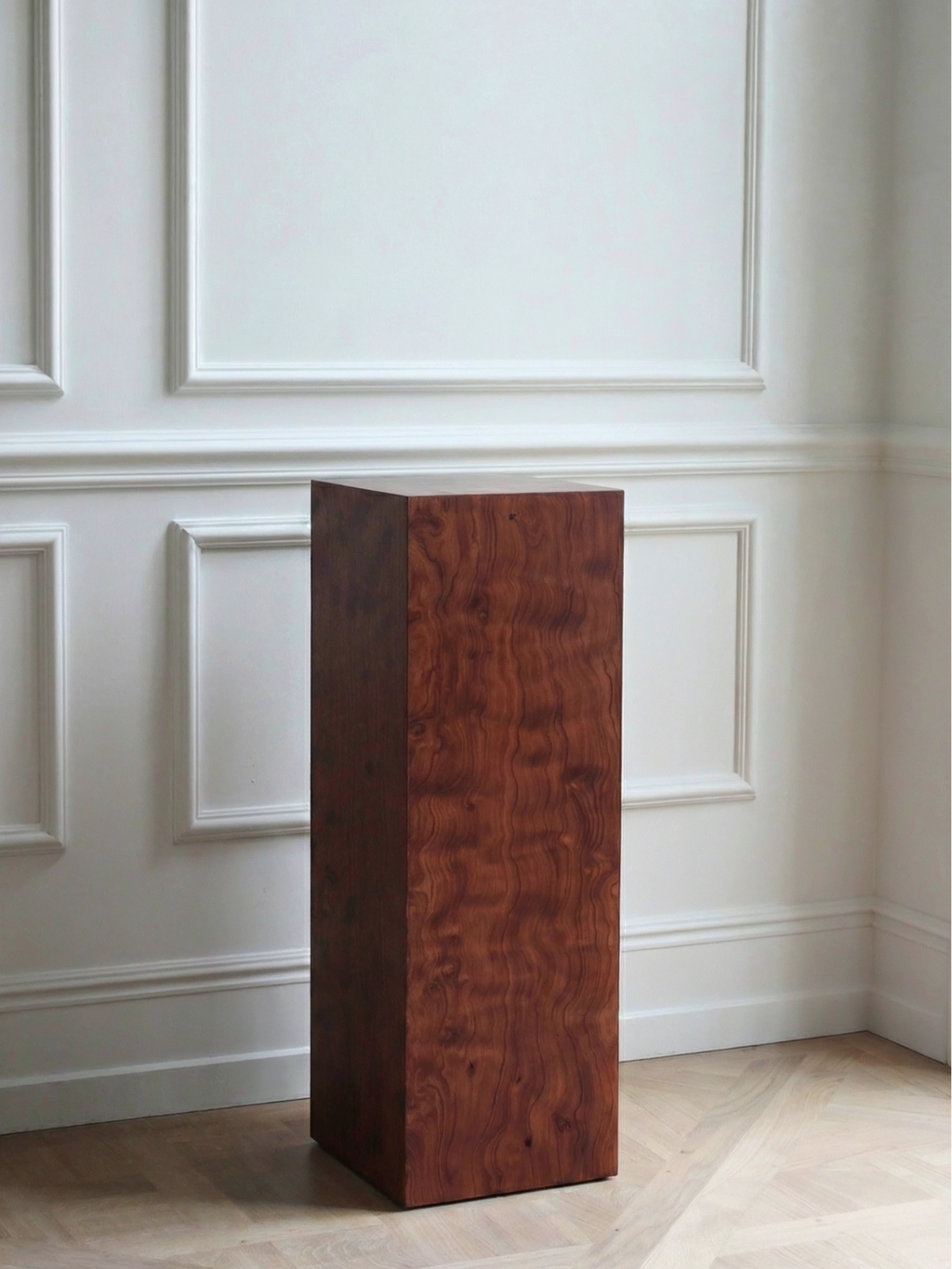 TCL Studios Monolith Pomele Display Column, a tall rectangular display column crafted from rich reddish-brown figured pomele wood with a striking wavy grain and smooth polished finish.