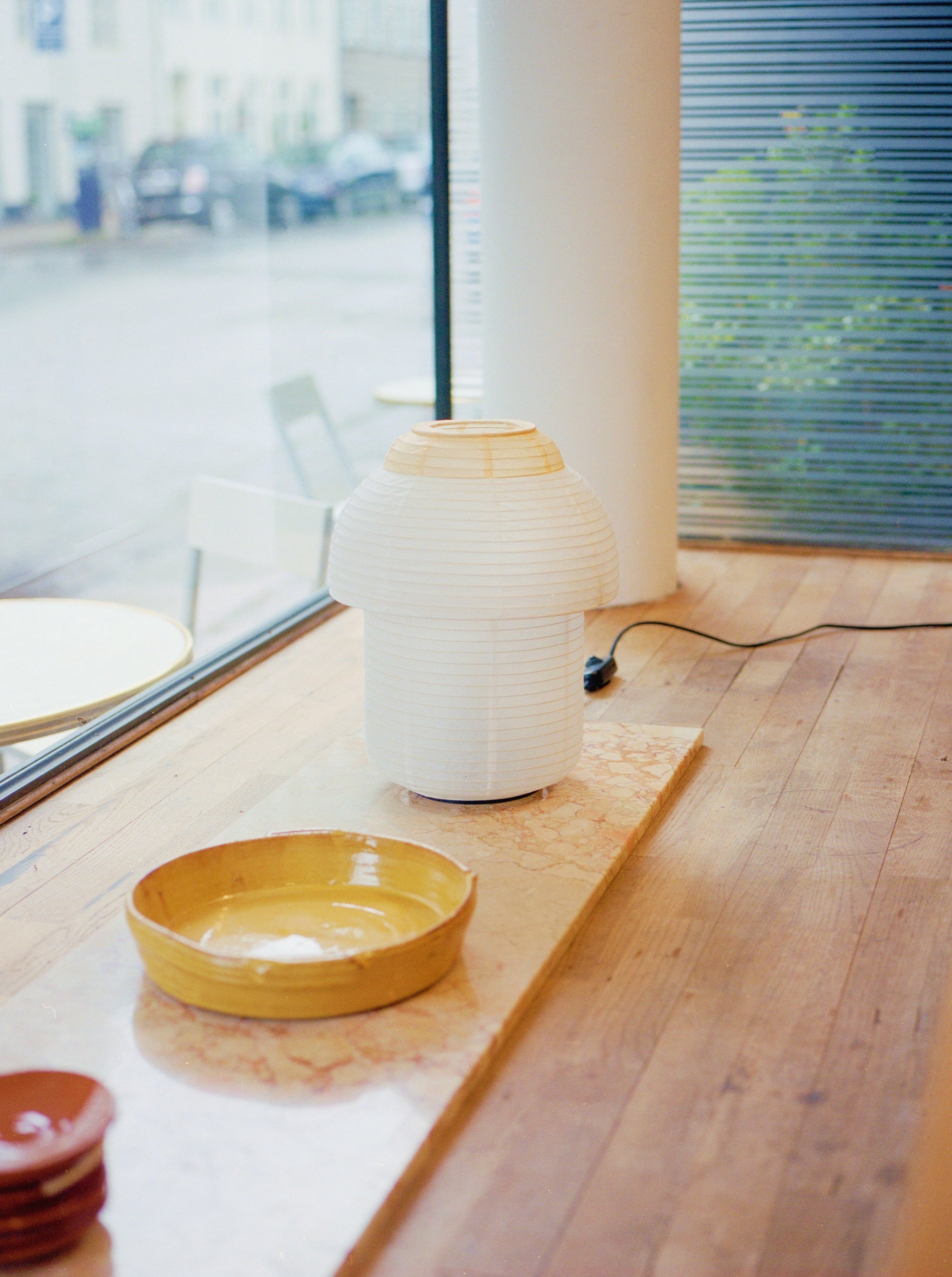 Made by Hand Papier Double Ø30 Table Lamp, an off-white paper table lamp with a distinctive mushroom-like silhouette and delicate ribbed texture, featuring a natural light wood ring accent. This modern minimalist paper lantern provides soft, ambient lighting, perfect for Scandinavian or japandi living rooms, bedrooms, or cozy reading nooks.