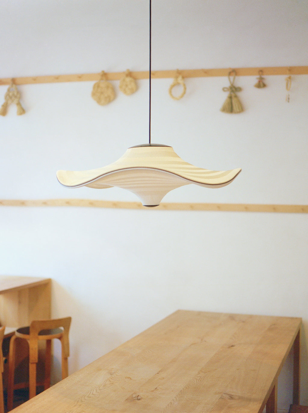 Made by Hand Flying Ø58 Pendant Lamp, a distinctive Scandinavian pendant light crafted from natural oak pressed wood veneer with a beautifully wavy, sculptural silhouette and contrasting dark accents. This organic modern ceiling light features a minimalist design, offering soft, diffused illumination. It's an ideal statement piece for a contemporary dining room, serene japandi living room, or minimalist bedroom.