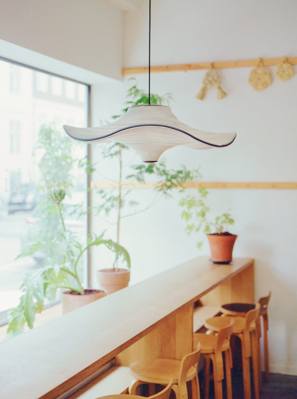 Made by Hand Flying Ø58 Pendant Lamp, a large organic modern pendant lamp featuring a wide, undulating form crafted from finely woven cream polypropylene ribbon, accented with a thin dark trim along its distinctive wavy edge.