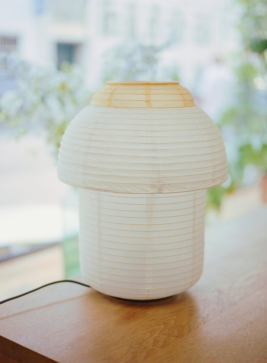 Made by Hand Papier Double Ø30 Table Lamp, a contemporary table lamp featuring a stacked mushroom-like silhouette with a creamy white pleated rice paper shade. It is accented by a light natural wood top, creating a soft, diffused glow perfect for minimalist and organic modern interiors. Ideal as a Japandi bedside table lamp or Scandinavian living room accent for serene home lighting.