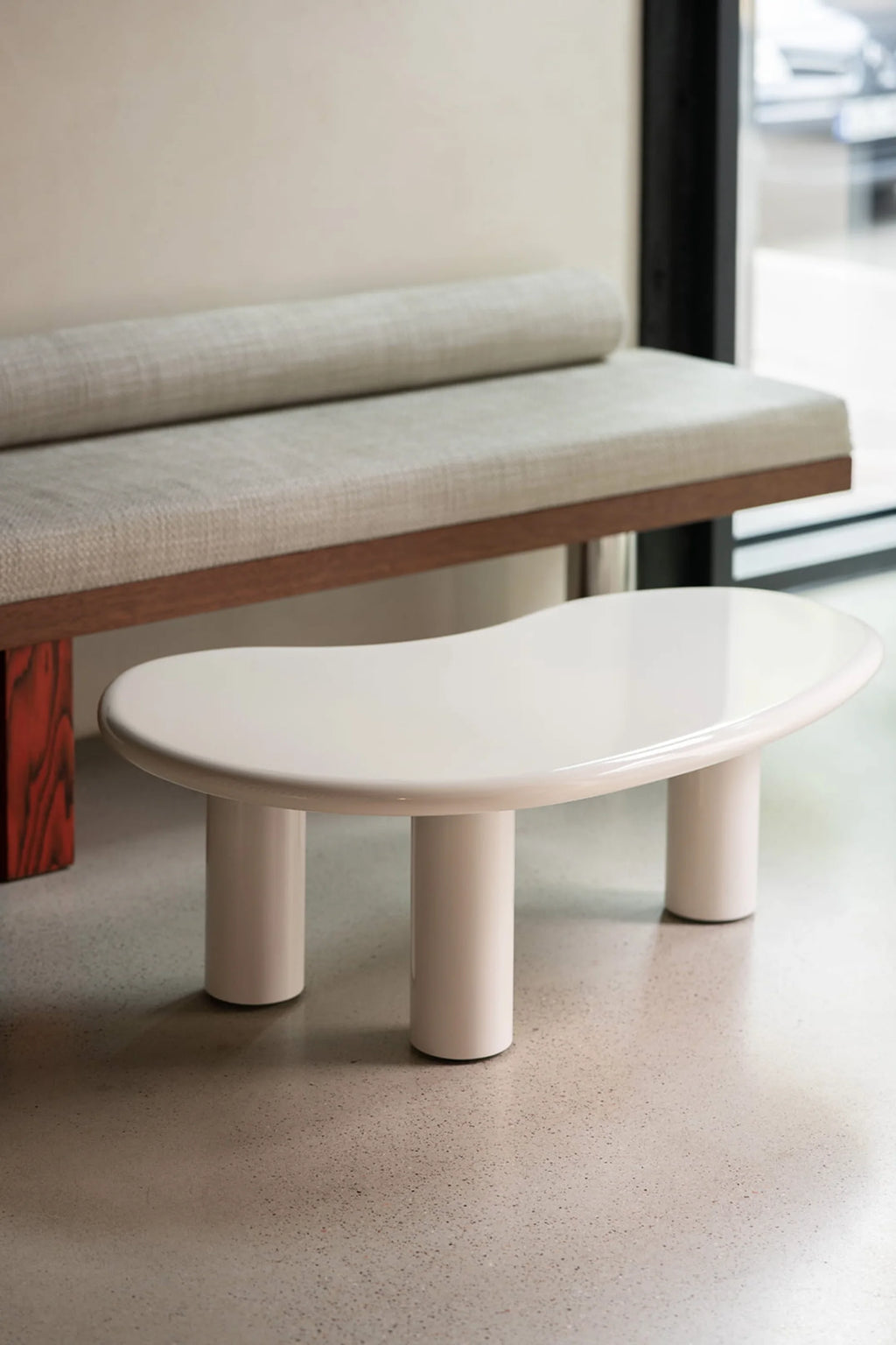 NG DESIGN Object 061 Coffee Table, a modern organic white glossy table with a kidney-shaped top and three cylindrical legs, displayed in a contemporary interior. Perfect for a chic living space.