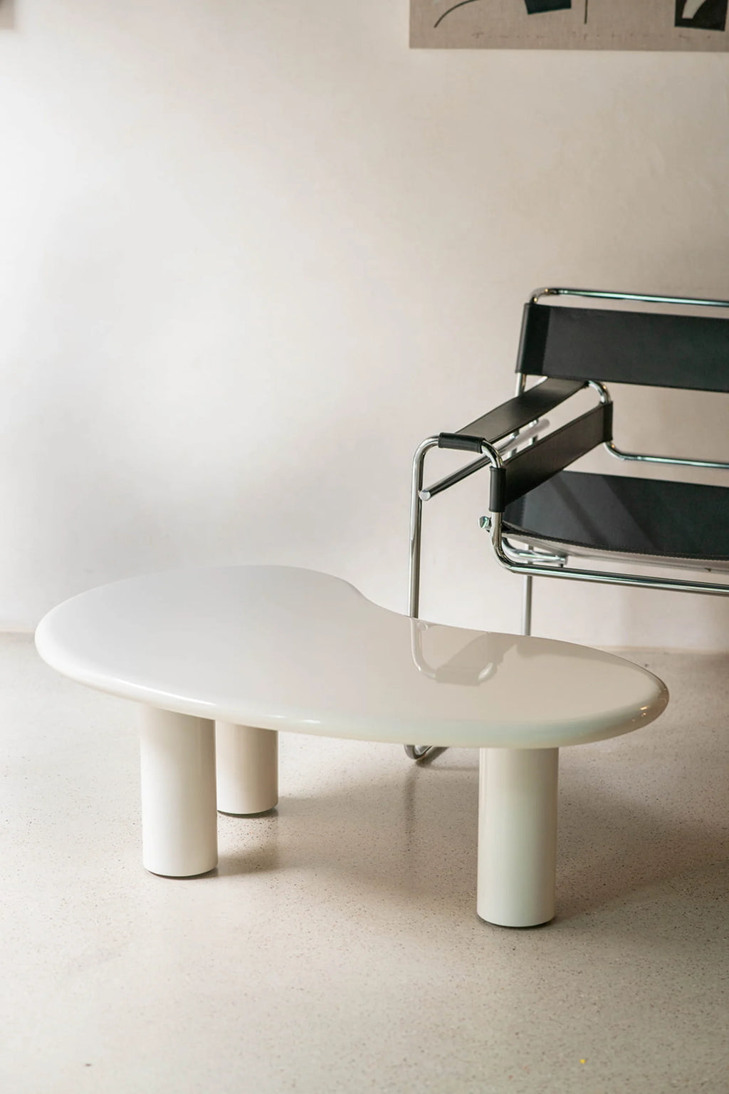 NG DESIGN Object 061 Coffee Table in a lifestyle shot. This premium modern coffee table is off-white with a unique organic-shaped top and three cylindrical legs, perfect for a contemporary living room.