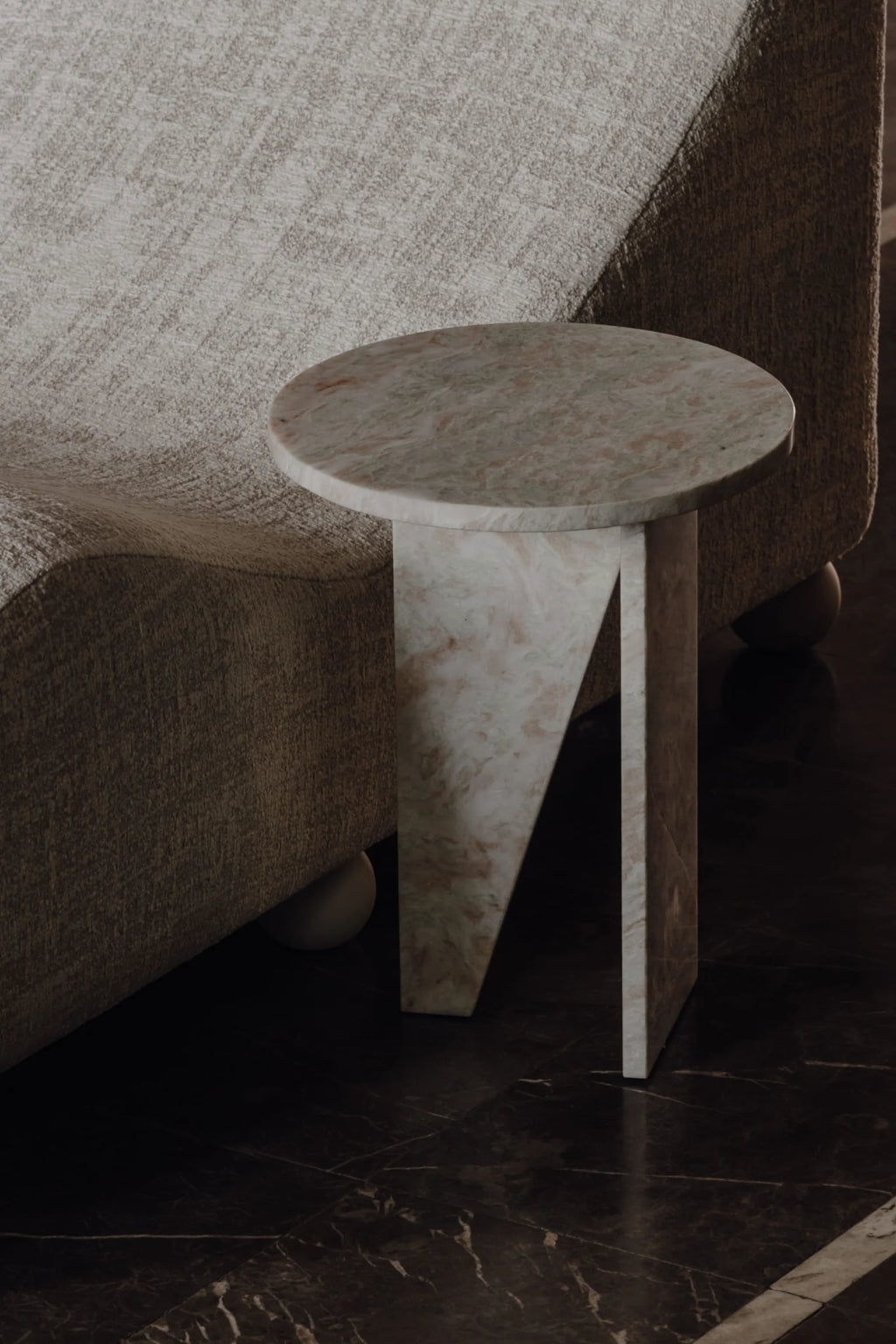 NG DESIGN Object 066 Side Table, a luxury handcrafted white and pink swirled concrete side table with a round top and geometric base, positioned beside a beige textured couch on dark marble flooring. Ideal for modern interior styling.