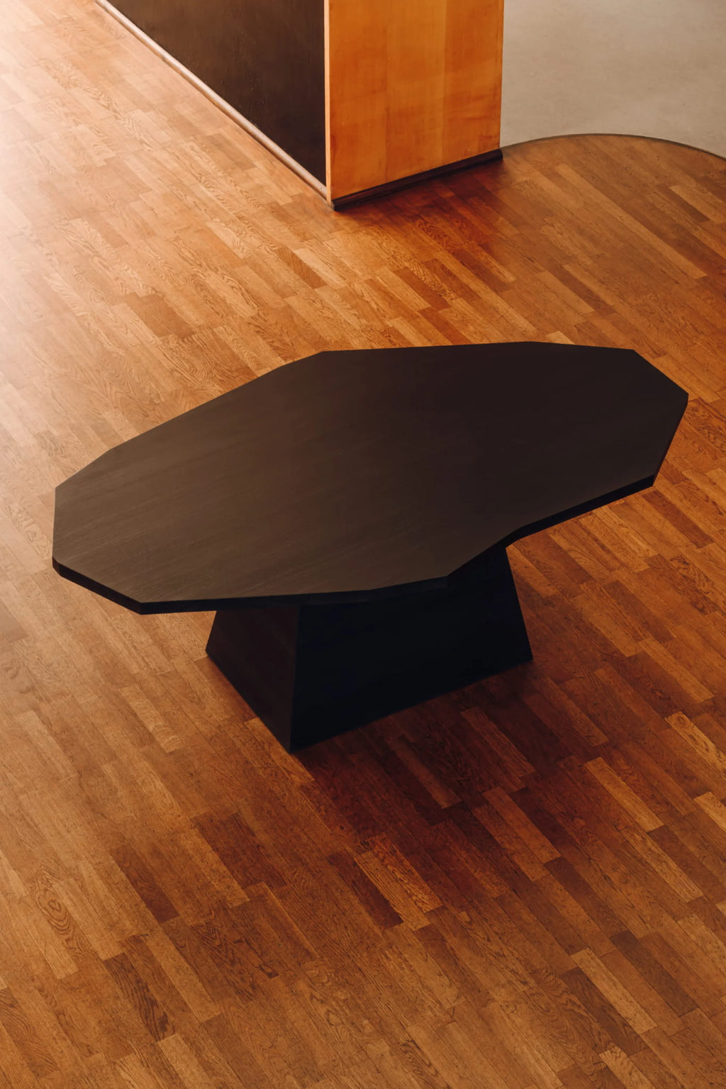 NG DESIGN Object 110 Dining Table, a luxurious modern black wooden octagonal tabletop on a solid block pedestal base, displayed on light brown hardwood flooring. Perfect for contemporary dining spaces.