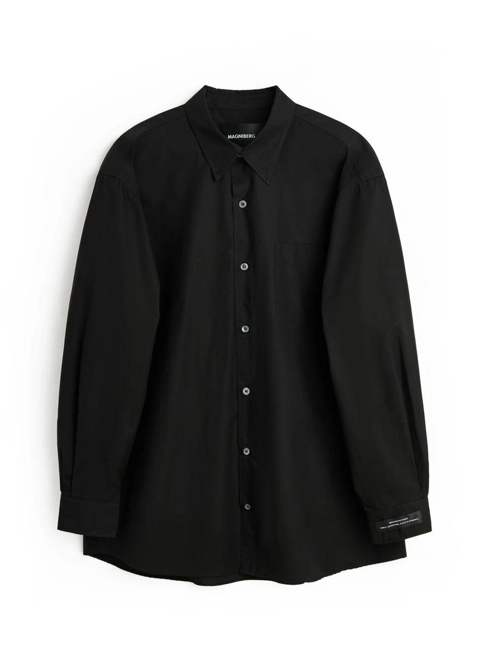 Magniberg Night shirt, a luxurious solid black cotton night shirt designed with an oversized, relaxed fit and a smooth, matte finish. This modern minimalist button-down features a classic collar, full-length sleeves, a single chest pocket, and subtle branding on the cuff for a refined touch. Ideal for contemporary sleepwear or as a versatile gender-neutral loungewear shirt for elevated comfort.