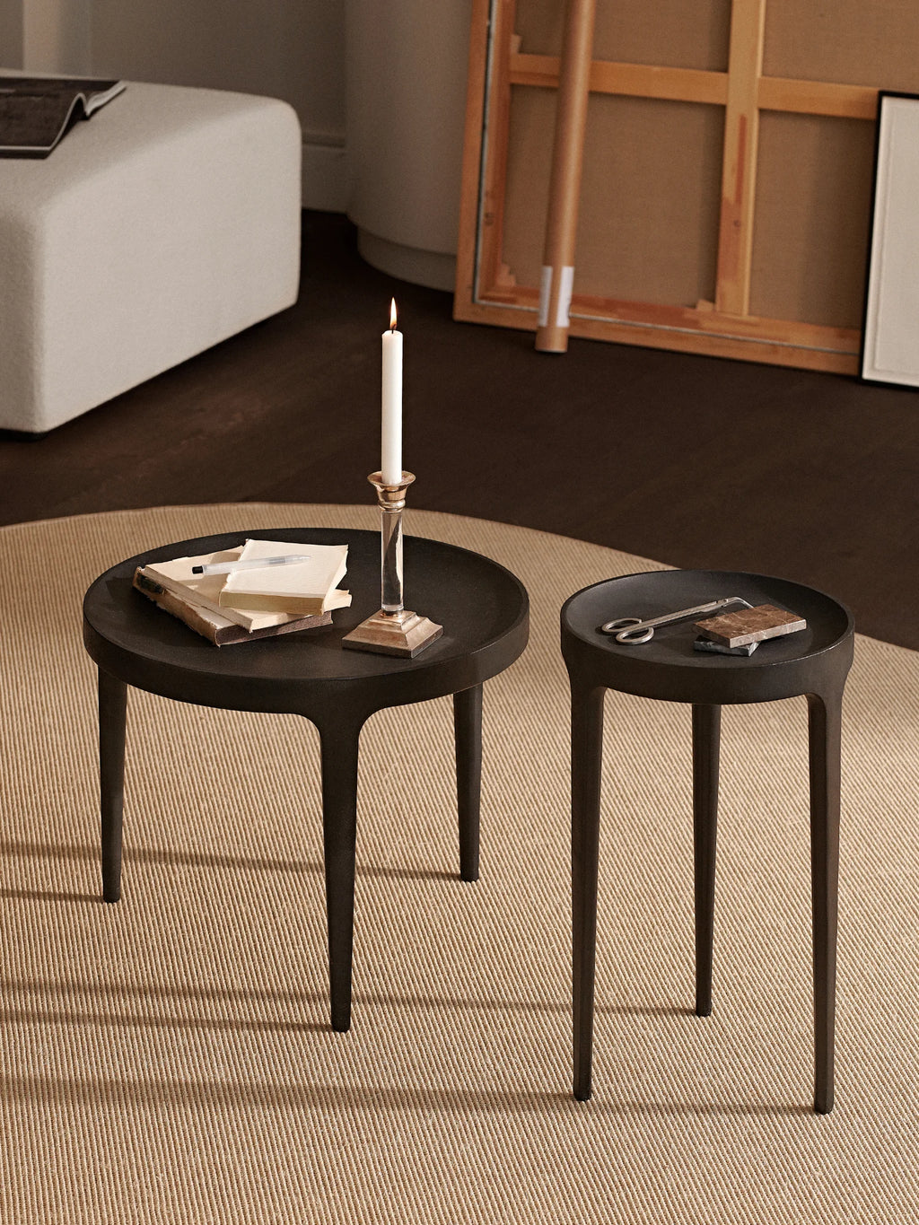NORR11 Ghost Side Table, a modern minimalist accent table with a sculptural, organic form, crafted from dark stained ash wood with a smooth matte black finish. It features a distinct round tabletop with a raised tray edge and three elegantly tapered legs that seamlessly flow into the top, creating a unified silhouette.