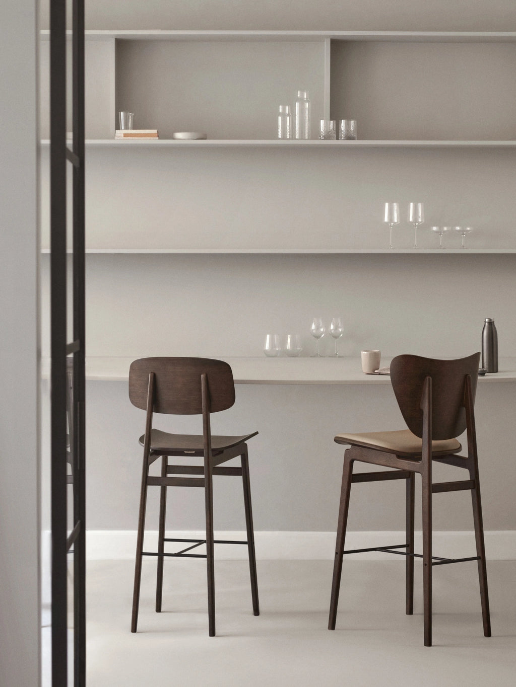 NORR11 Elephant Counter Chair, a sculptural mid-century modern bar stool featuring a dark stained solid wood frame with an elegantly curved backrest and sturdy tapered legs.