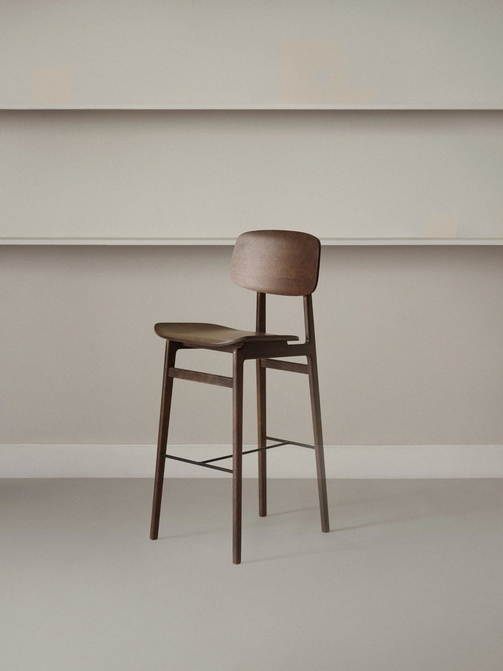 NORR11 NY11 Bar Chair, a minimalist Scandinavian bar stool crafted from rich dark solid oak wood, featuring an ergonomically curved seat and backrest, slender tapered legs, and.