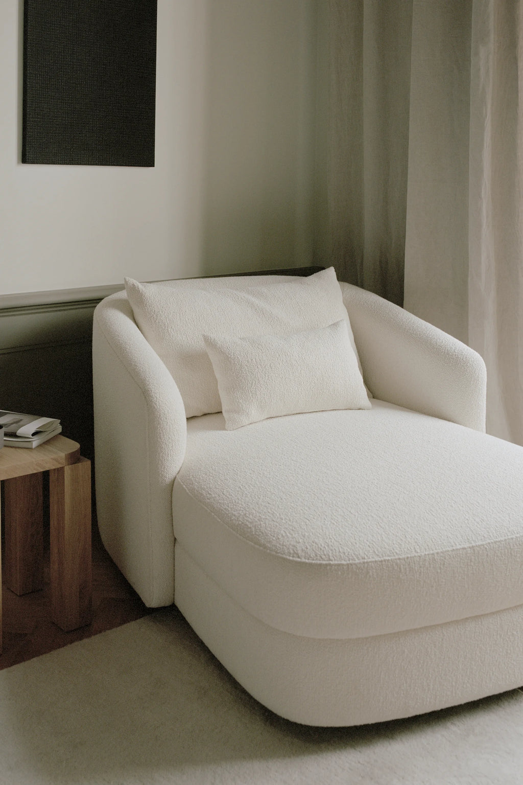 New Works Covent Chaise Lounge, an organic modern lounge chair upholstered in a plush cream bouclé fabric with a soft, textured finish and elegantly curved profile. Its sculptural design features a gentle recline and rounded edges, offering a luxurious and inviting seat. Perfect as a statement piece in a contemporary living room, minimalist bedroom, or cozy reading nook.