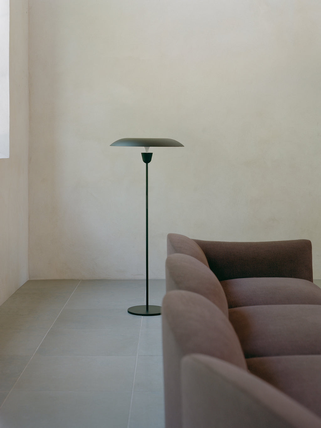 New Works Kantarell Floor Lamp, a modern minimalist floor lamp crafted from matte dark green powder-coated steel with a slim cylindrical stand, sturdy round base, and a distinctive disk-shaped shade. This elegant Scandinavian design provides diffused ambient lighting, perfect for contemporary living rooms, cozy reading nooks, or sophisticated bedroom accents. Ideal for enhancing modern interiors with its clean lines and subtle color.