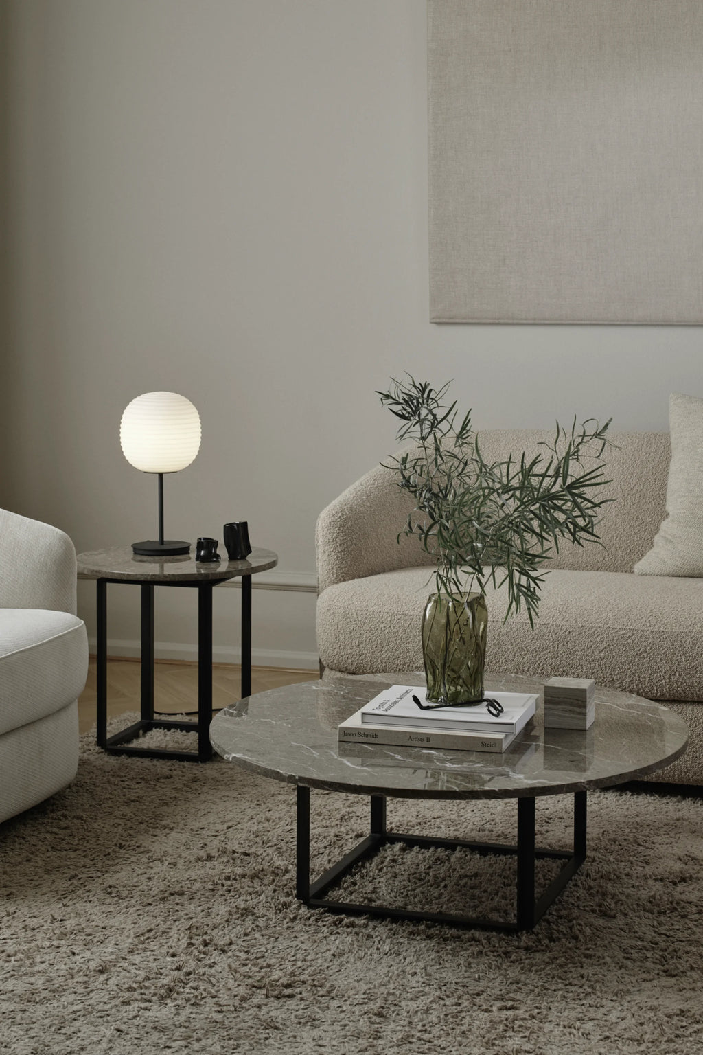 New Works Florence Side Table, a modern minimalist side table featuring a round grey veined marble top with a polished finish, supported by a sleek matte black metal frame. Its contemporary design and natural stone texture make it a versatile accent piece for living rooms or bedrooms, blending seamlessly into organic modern or Scandinavian interiors.