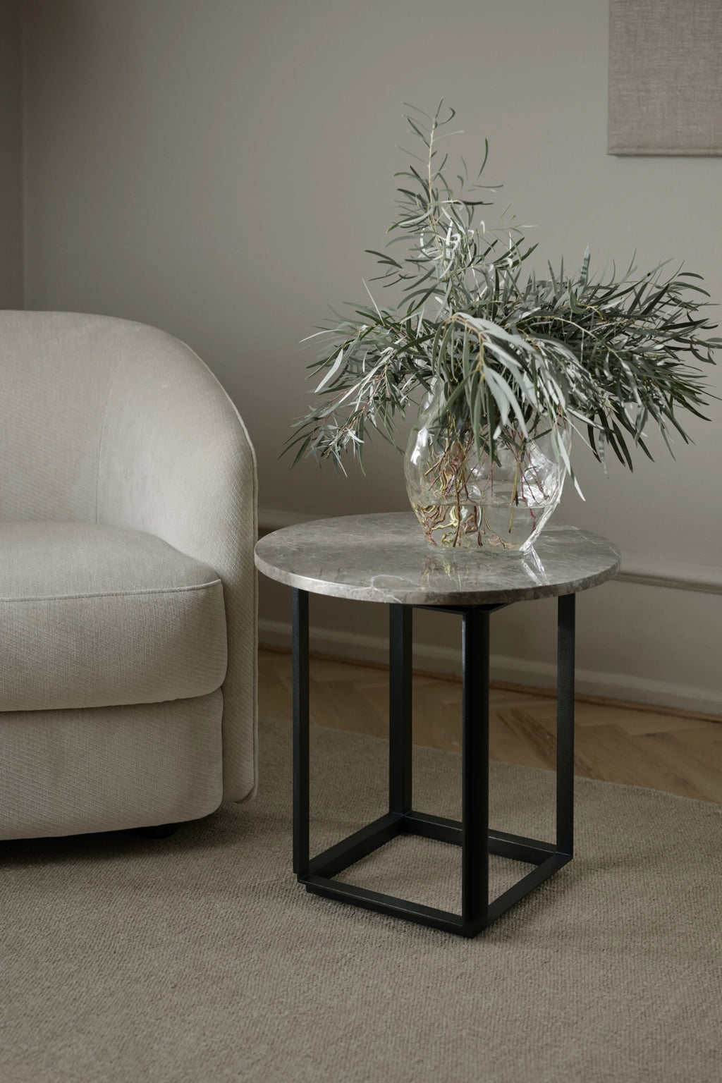 New Works Florence Side Table, a contemporary round side table featuring a polished grey marble top with intricate natural brown veining, supported by a sleek matte black metal geometric base. This modern minimalist accent table is ideal for Scandinavian living rooms or as a sophisticated bedside table in bedrooms.