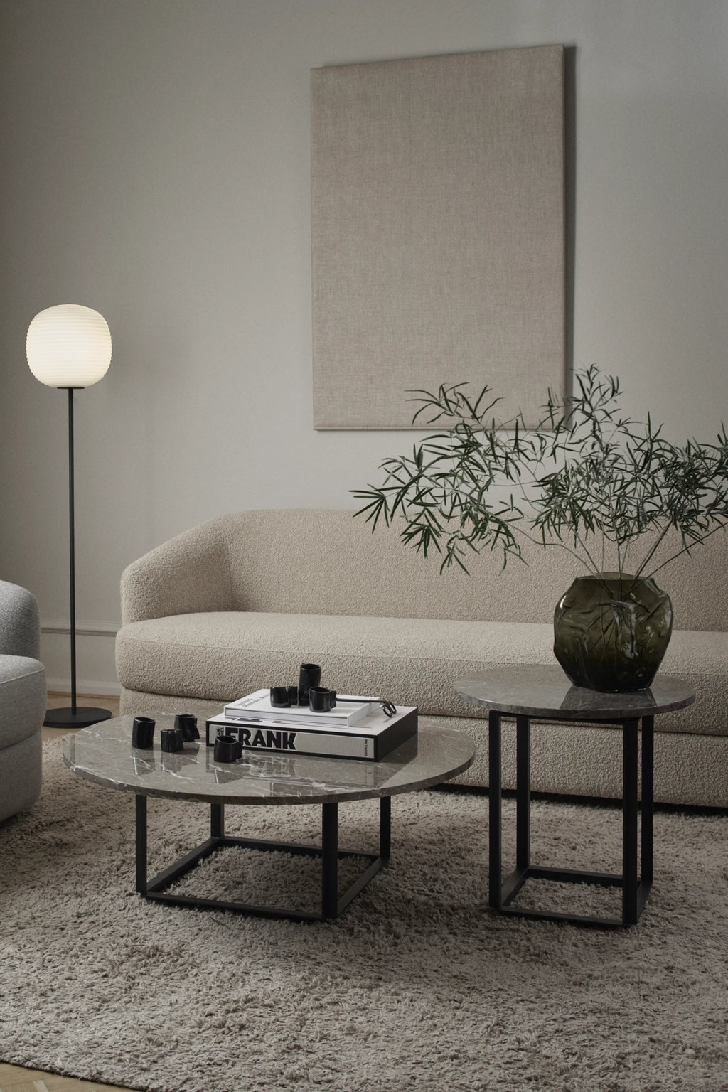 New Works Florence Side Table, a sleek modern side table featuring a round polished grey marble top with elegant white veining, supported by a minimalist matte black metal frame. This contemporary accent table, with its Scandinavian design, is perfect for a stylish living room or bedroom.