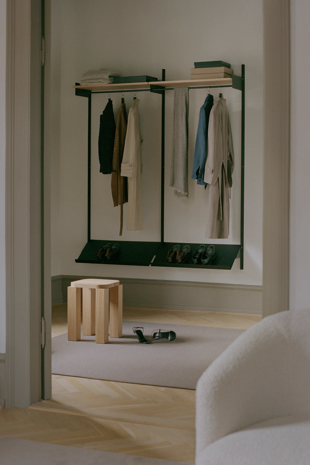 Atlas Stool and clothing rack by New Works with hanging clothes in a minimalistic room setting