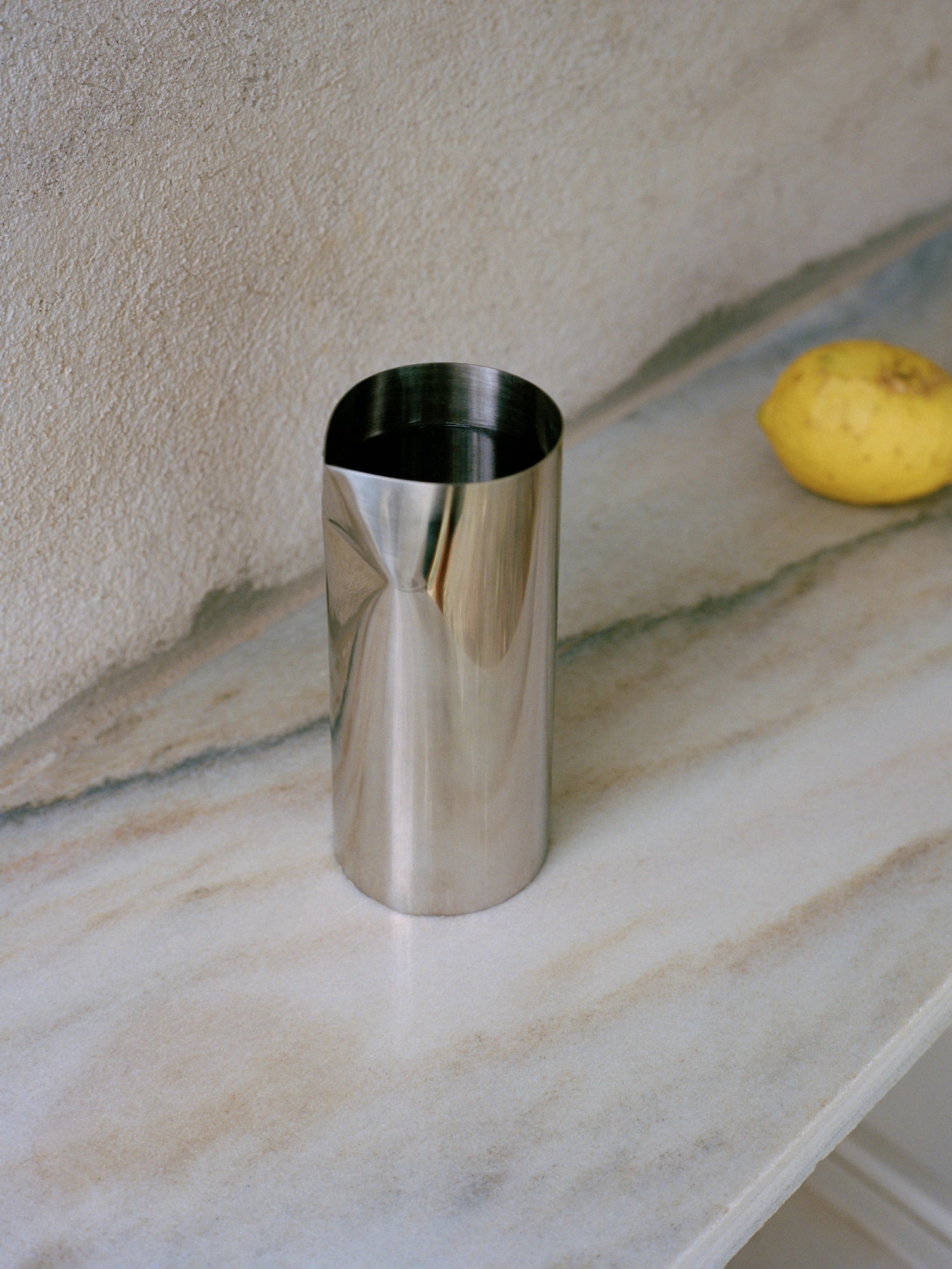 New Works Pleat Pitcher in polished silver metal, featuring distinctive vertical pleats on a narrow, modern design. A luxury premium serveware piece.