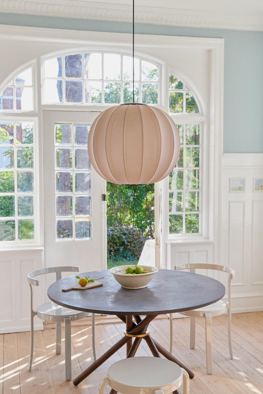 Made by Hand Knit-Wit Ø60 Round Pendant Lamp, a large spherical knitted fabric pendant lamp in a warm beige oatmeal color, featuring a subtly textured surface and distinct ribbed segments. This modern minimalist ceiling light, with its organic form and inviting Scandinavian design, casts a soft, diffused glow.