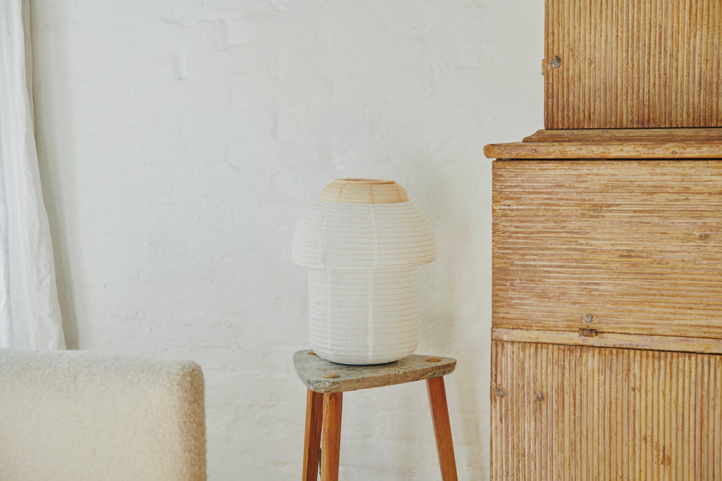 Made by Hand Papier Double Ø30 Table Lamp, a contemporary japandi style table lamp featuring a unique stacked silhouette with an off-white rice paper shade and delicate horizontal ribbing. Its natural light wood top and base complement the organic modern design, providing soft, diffused lighting for serene spaces. Ideal as a Scandinavian bedside lamp, minimalist desk lamp, or for wabi-sabi shelf styling.