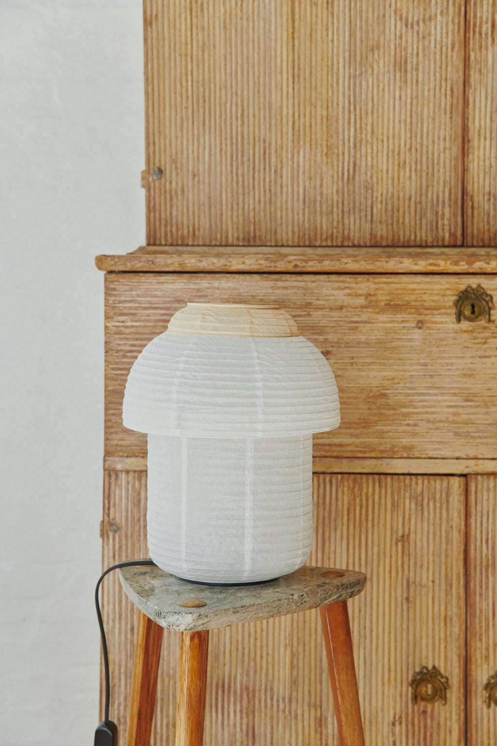 Made by Hand Papier Double Ø30 Table Lamp, an off-white pleated paper table lamp with a distinctive mushroom-like silhouette and natural paper top, reflecting a Japandi minimalist design. This organic modern lamp provides soft, ambient lighting perfect for Scandinavian bedrooms, living room accent tables, or contemporary shelf styling.