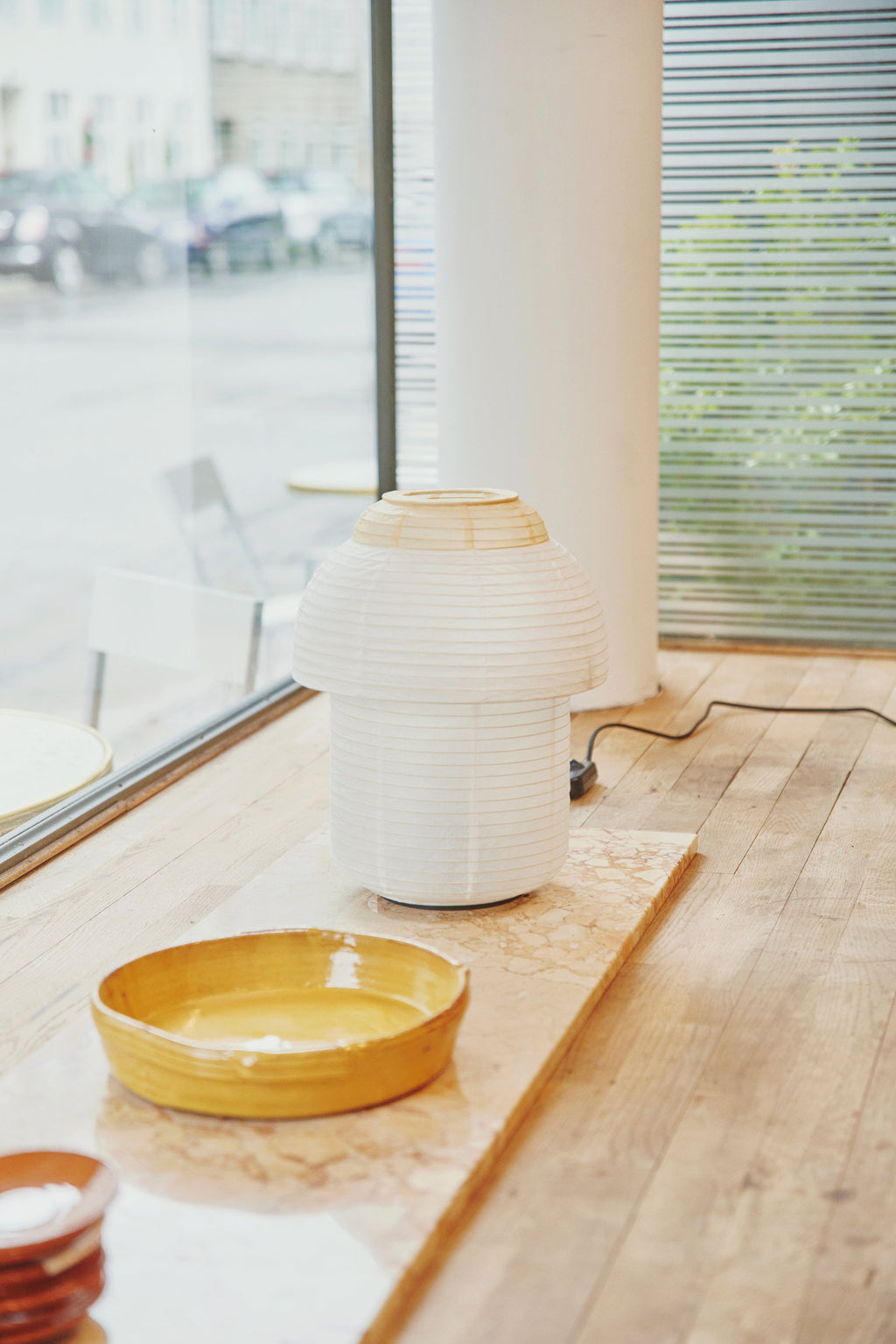 Made by Hand Papier Double Ø30 Table Lamp, an off-white pleated paper lamp with a distinctive mushroom-like silhouette and a natural wood ring accent at the top, offering a soft, diffused glow.