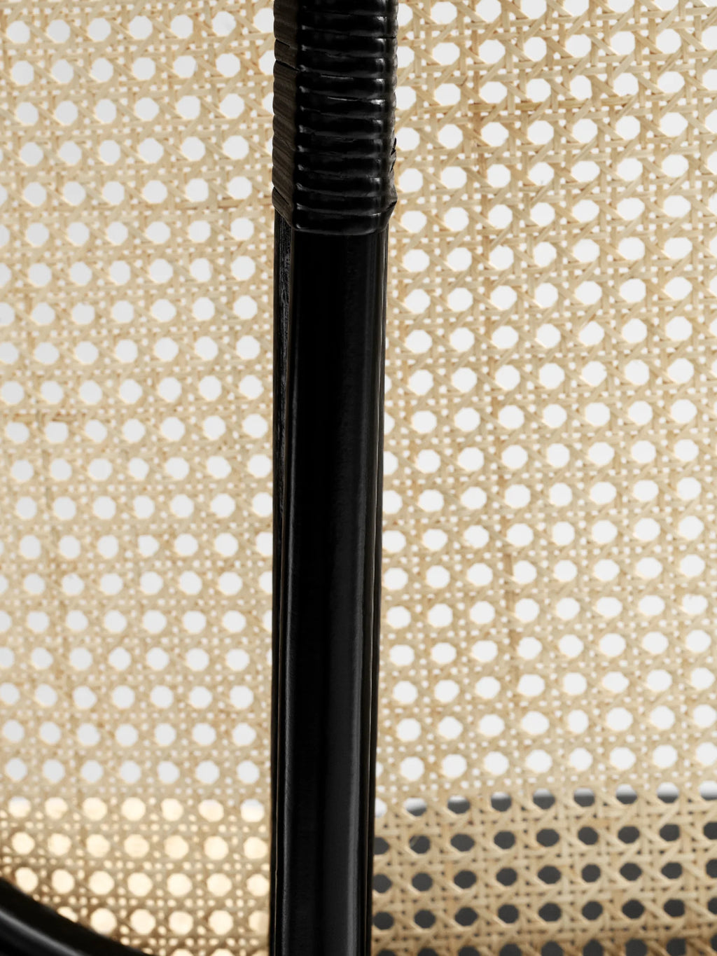 NORR11 Nomad Chair, a modern lounge chair featuring a natural woven cane seat and backrest with a sleek black frame. This elegant chair is perfect for adding a touch of handcrafted style to any contemporary living space.