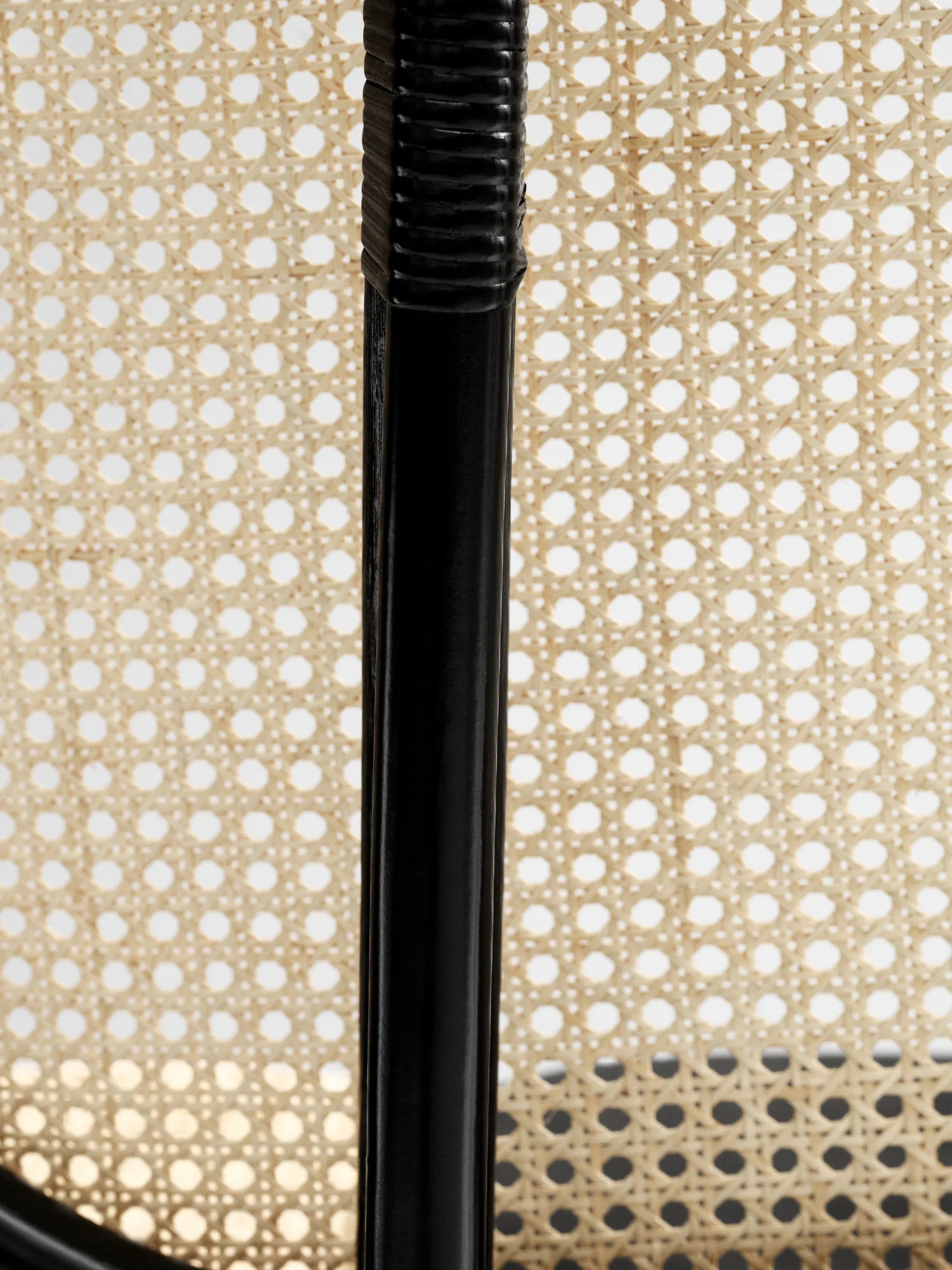 NORR11 Nomad Chair, a modern lounge chair featuring a natural woven cane seat and backrest with a sleek black frame. This elegant chair is perfect for adding a touch of handcrafted style to any contemporary living space.