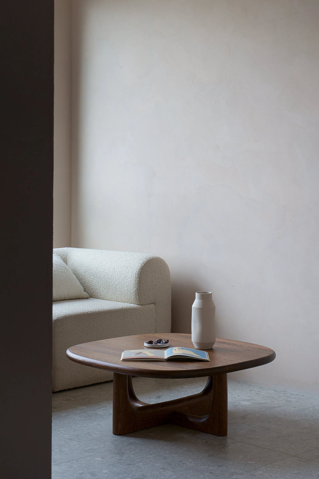 TAMO Olfo Coffee Table, a premium solid dark wood oval table with unique curved legs, displayed in a minimal living room setting. Ideal for modern spaces.