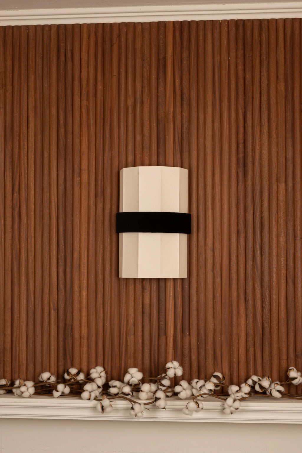 Simone & Marcel Okla Wall Light, a modern geometric wall sconce featuring a cream-colored octagonal body with a smooth matte finish, accented by a bold matte black velvet band.
