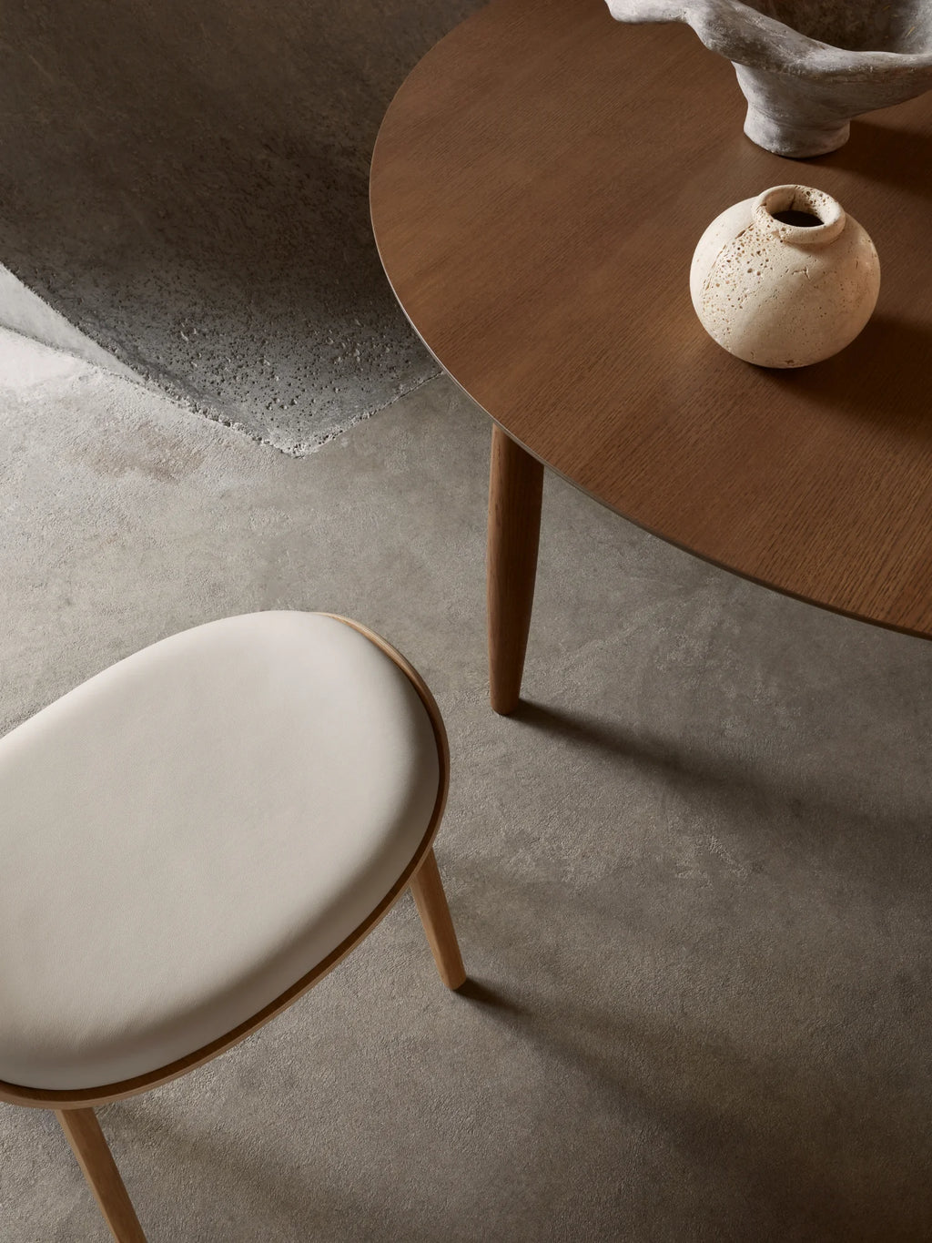 NORR11 Oku Round Dining Table, a modern and elegant round dining table crafted from rich, dark wood with tapered legs. This stylish piece is perfect for contemporary dining rooms.